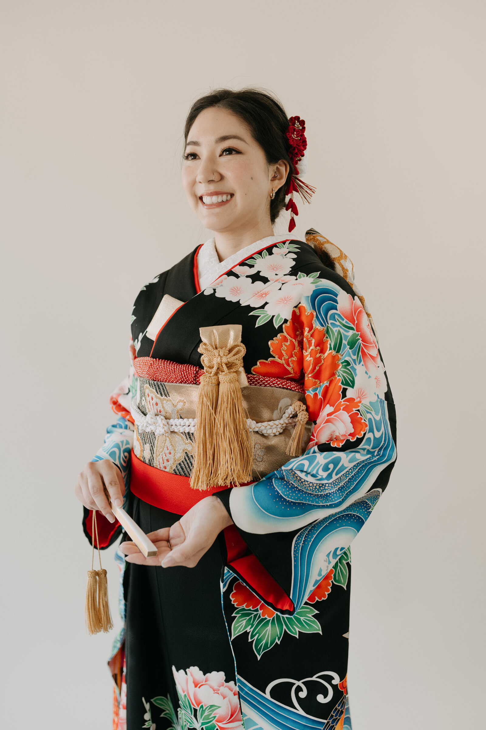 Bride in black wedding kimono rental with vivid peony and pheasant design holding a fan in Los Angeles studio | 黒引き振袖レンタル 豪華牡丹と雉柄 扇子を持つ花嫁 スタジオポートレート