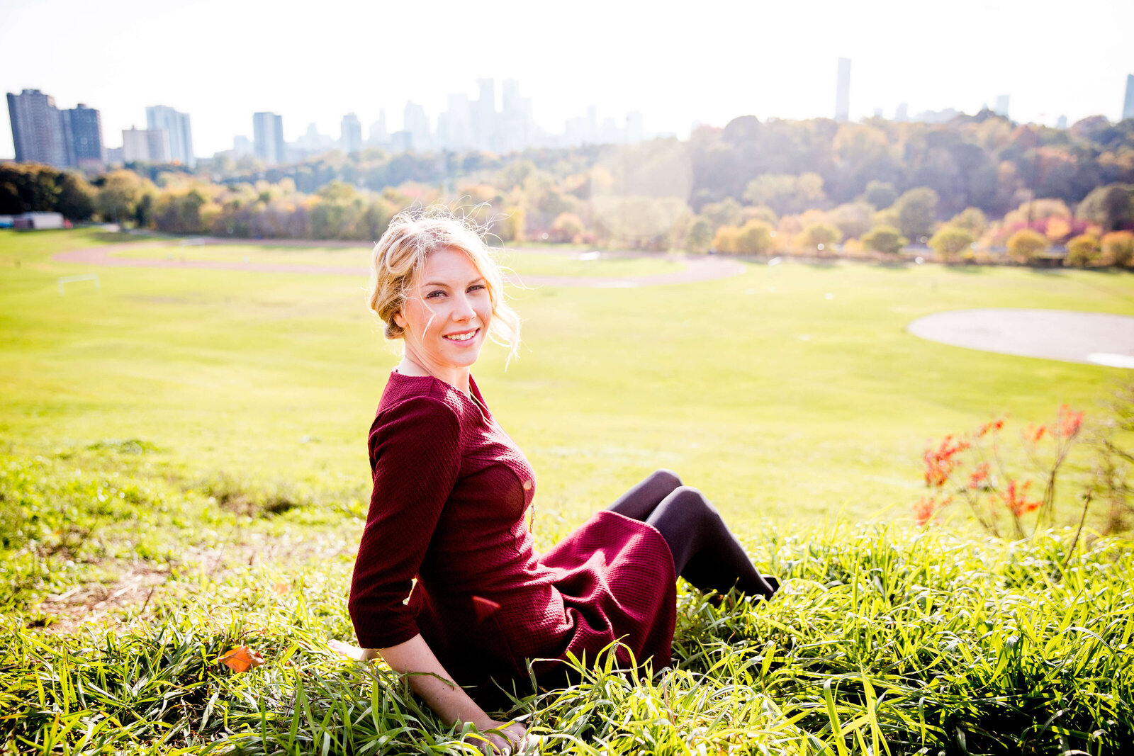 Woman sits in the grass atop Riverdale Park.