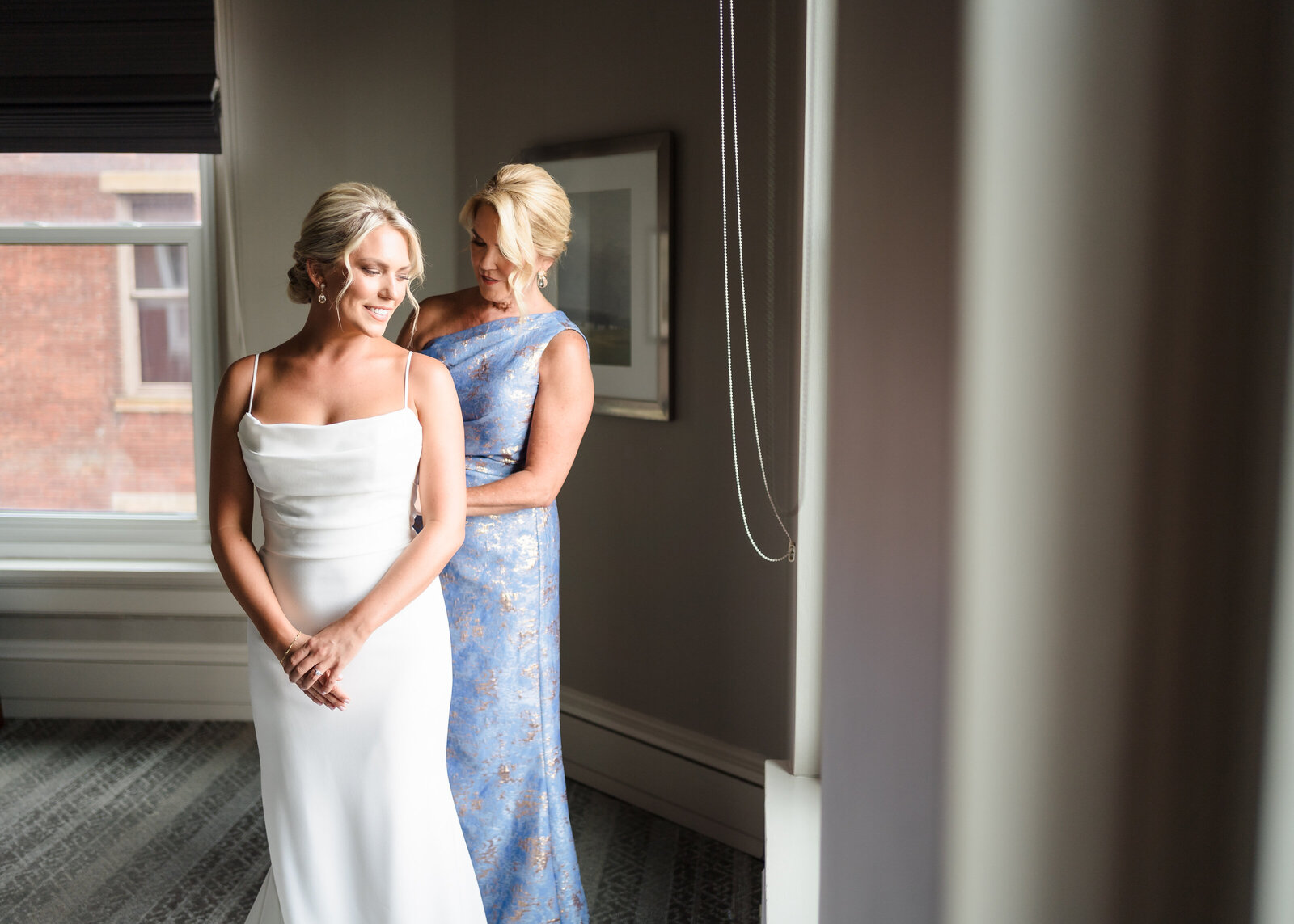 Mother of the bride helps her daughter zip up her dress inside the suite at the Westin