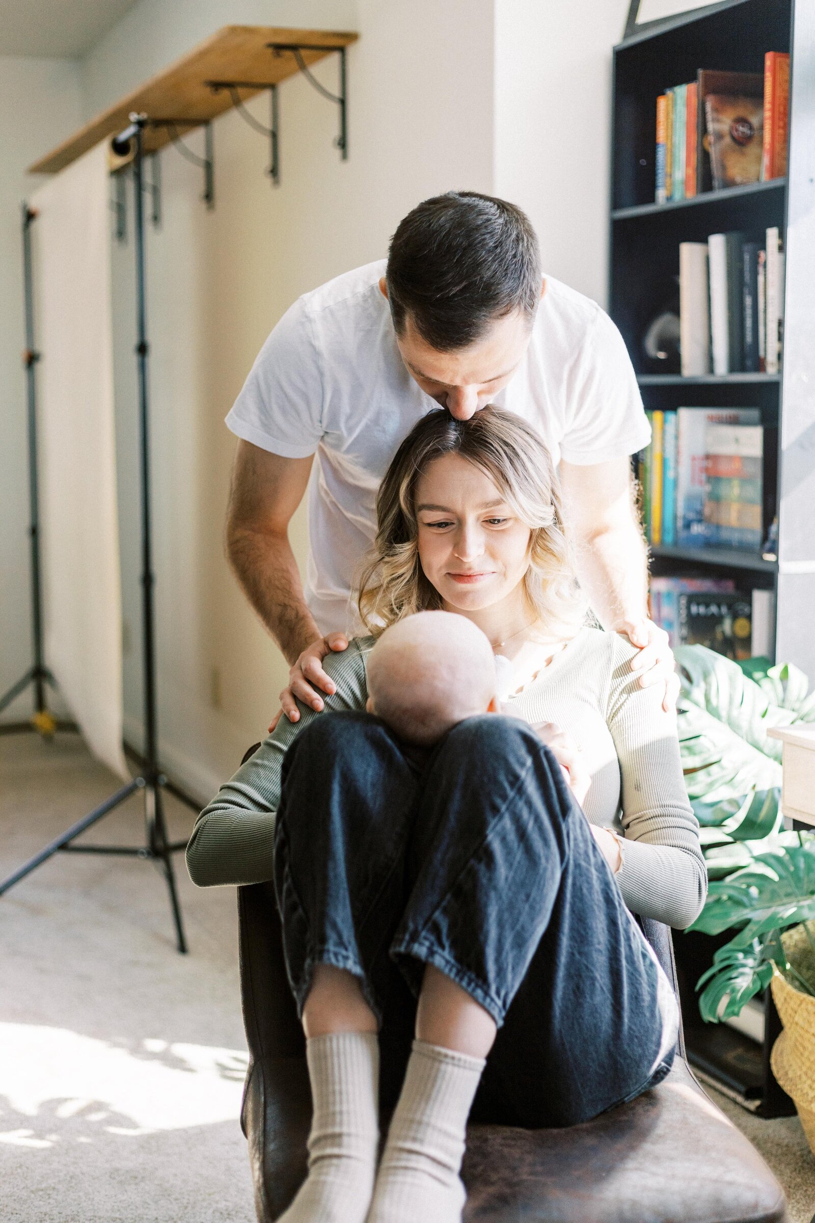 dad kissing mom's head while mom looks at baby in peoria illinois family photos 