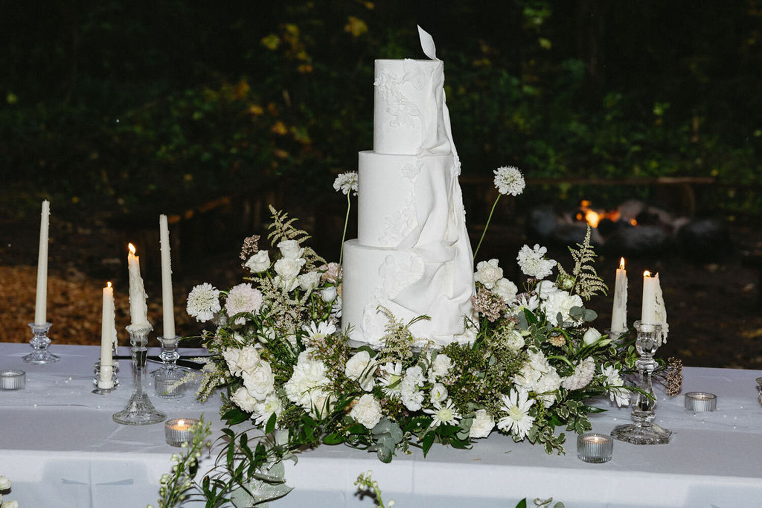 White wedding cake on a decorated table surrounded by flowers