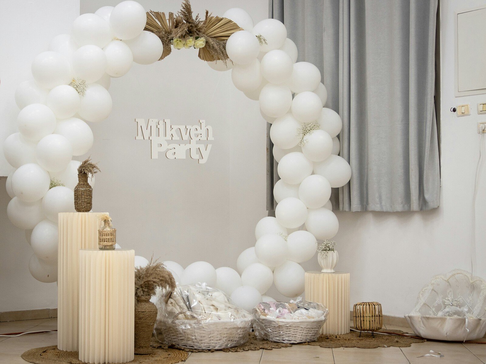 Minimalist white balloon arch with baskets and “Mikveh Party” sign