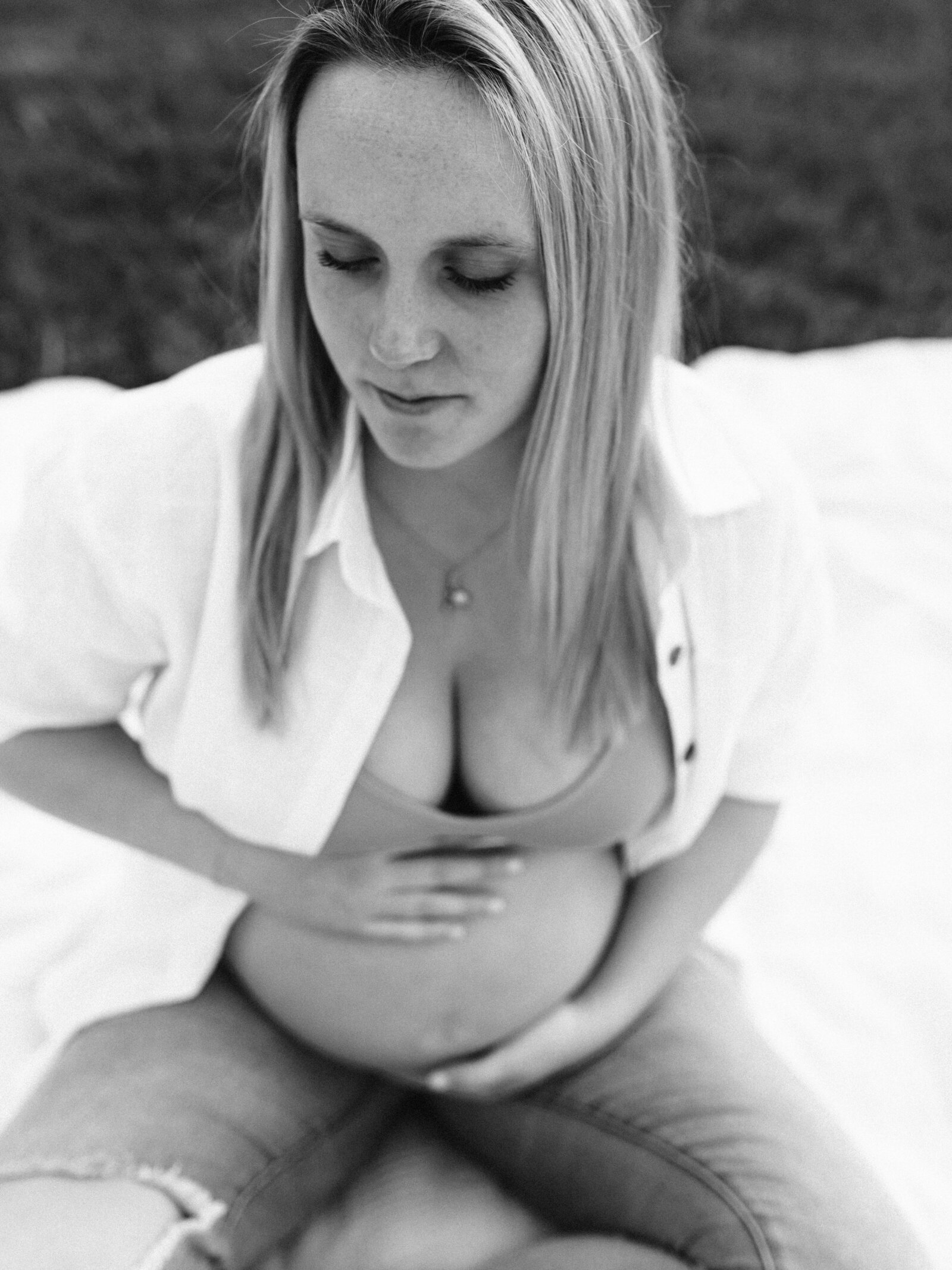 pregnant mother sitting and holding belly for maternity photoshoot