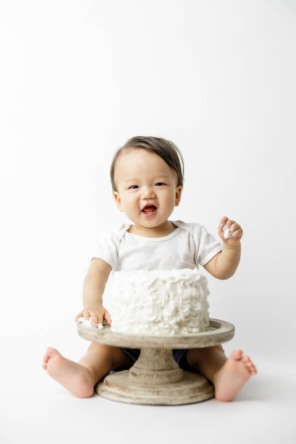 Baby laughs while eating cake.