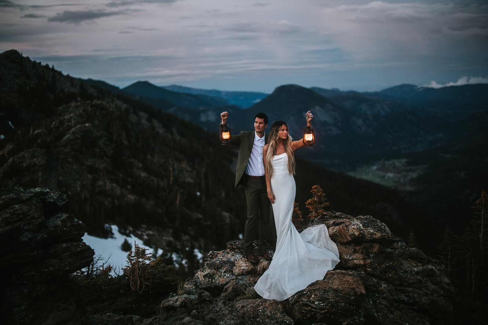 Couple at the top of a mountain posing for their destination elopement photographer