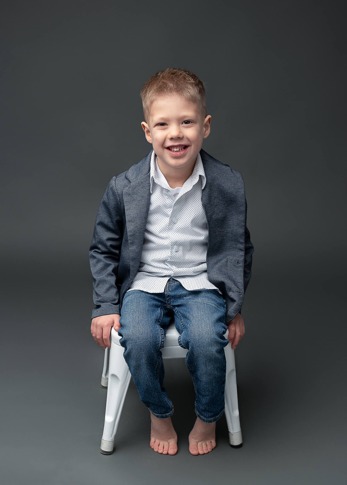 modern studio portrait of boy on a stool