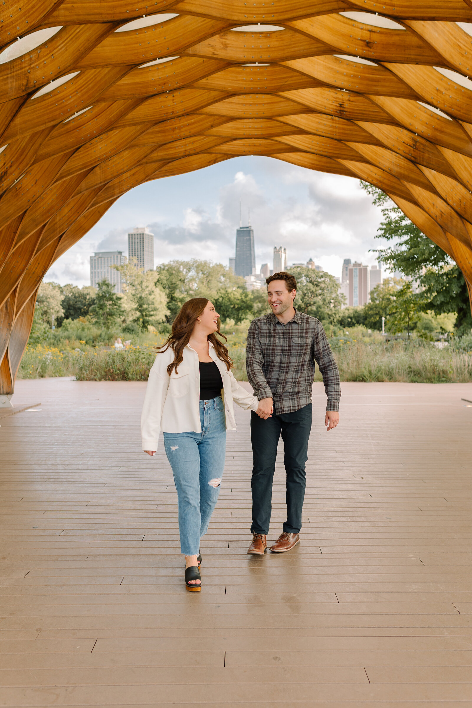 Young couple walking together while holding hands under the honeycomb sculpture in Chicago