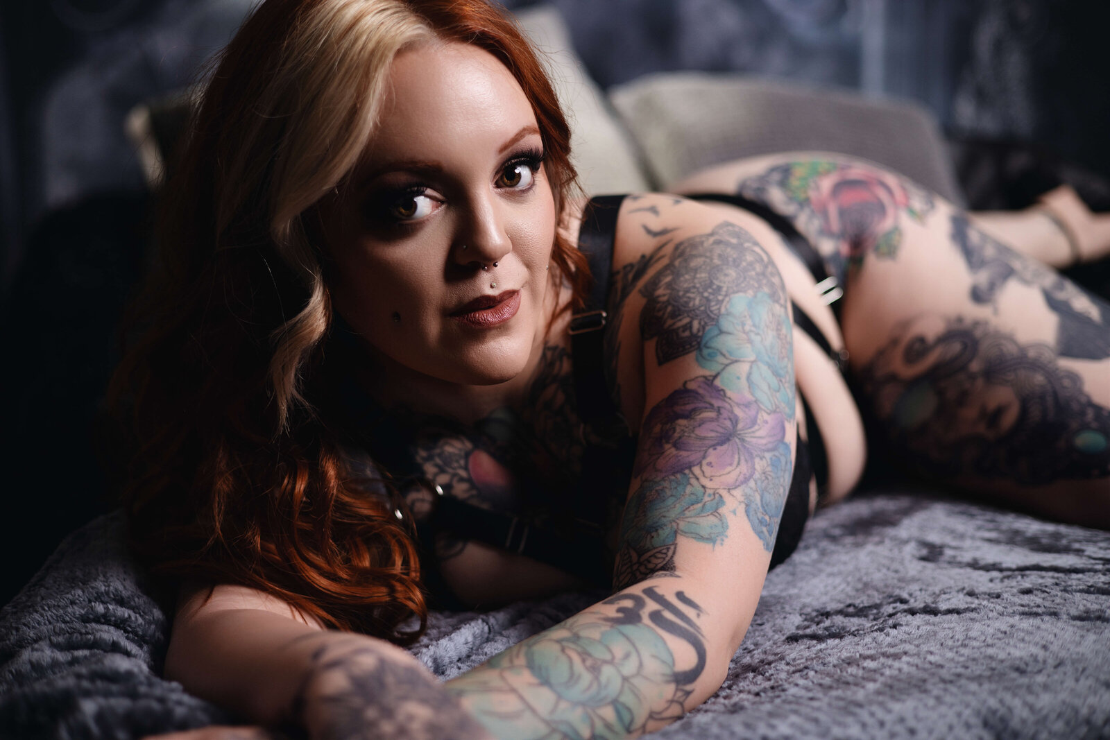 woman with tattoo's laying on stomach looking at camera