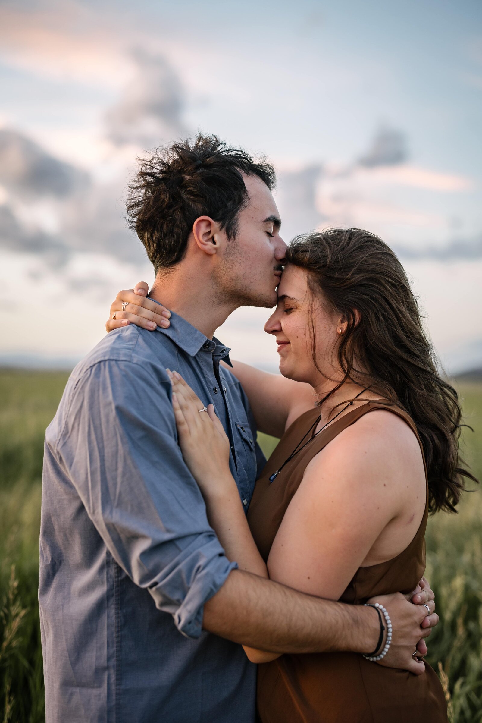 groom kissing bride on forehead at sunset