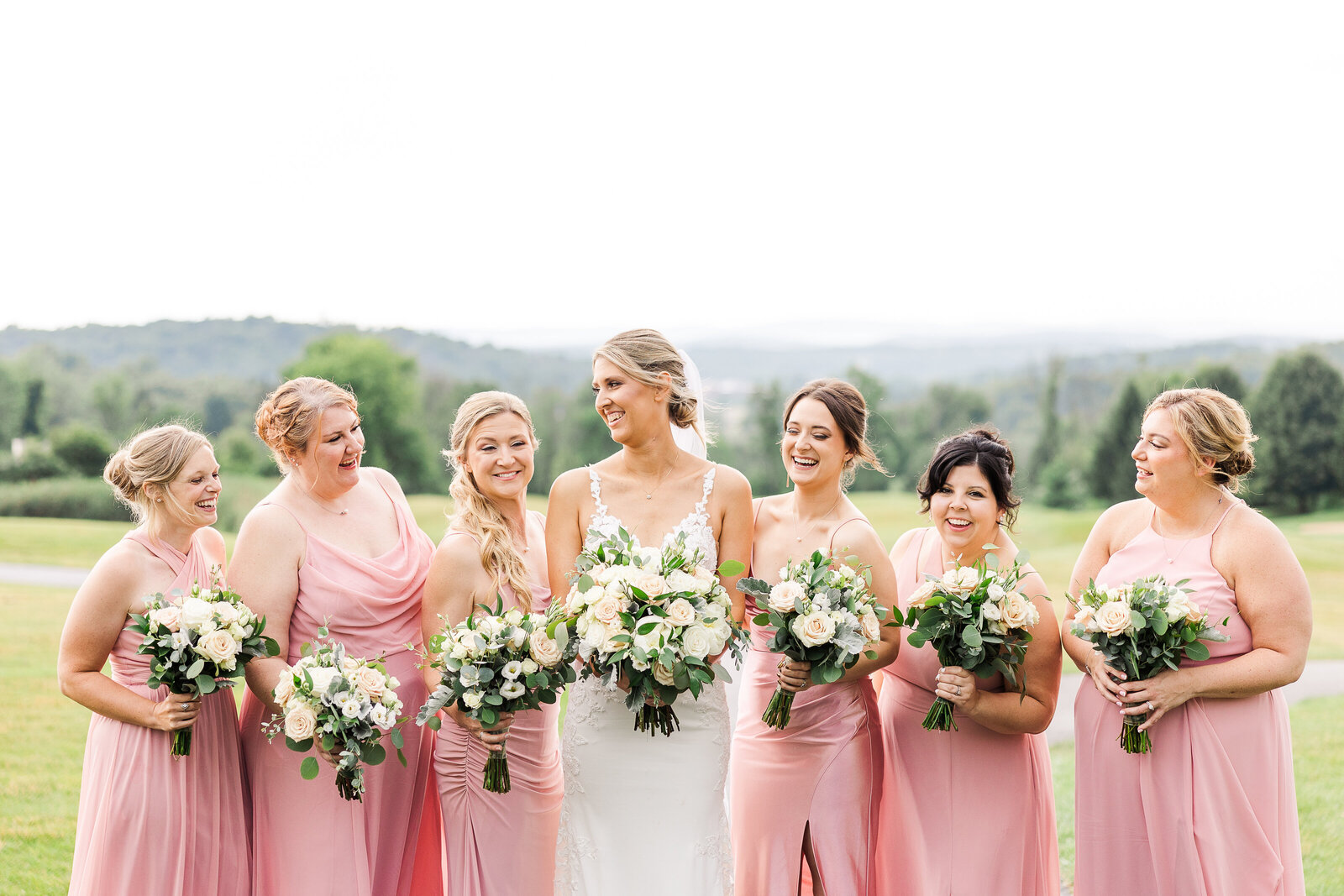 Up-close view of bridesmaids' floral bouquets and pink dresses at SkyView Golf Club