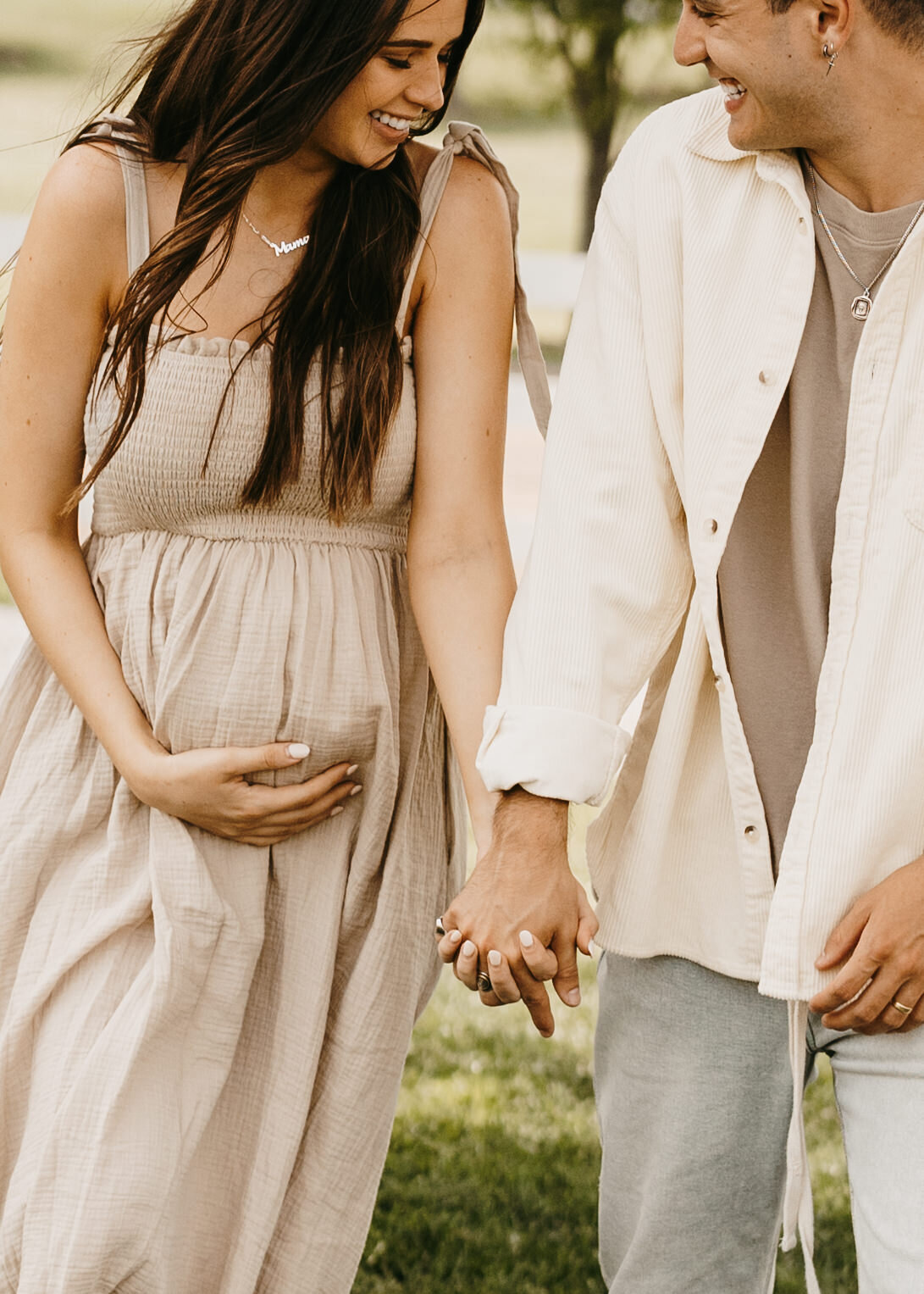 Jess and Gabriel Conte holding hands in a field for their maternity session