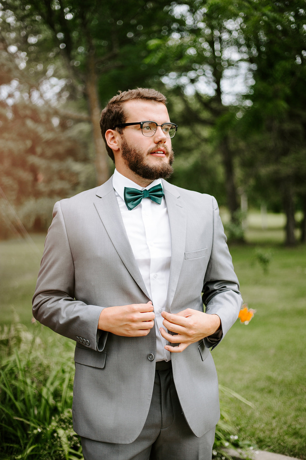 Groom holding his suit coat while smiling into the distance during his Minneapolis wedding