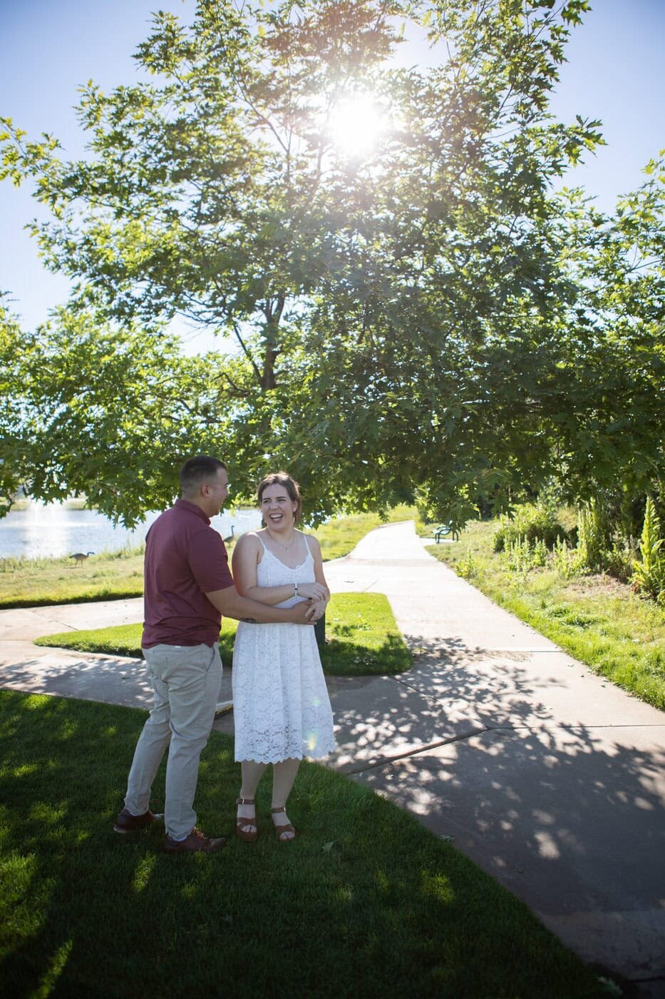 A couple dances together under a green tree in the sun.