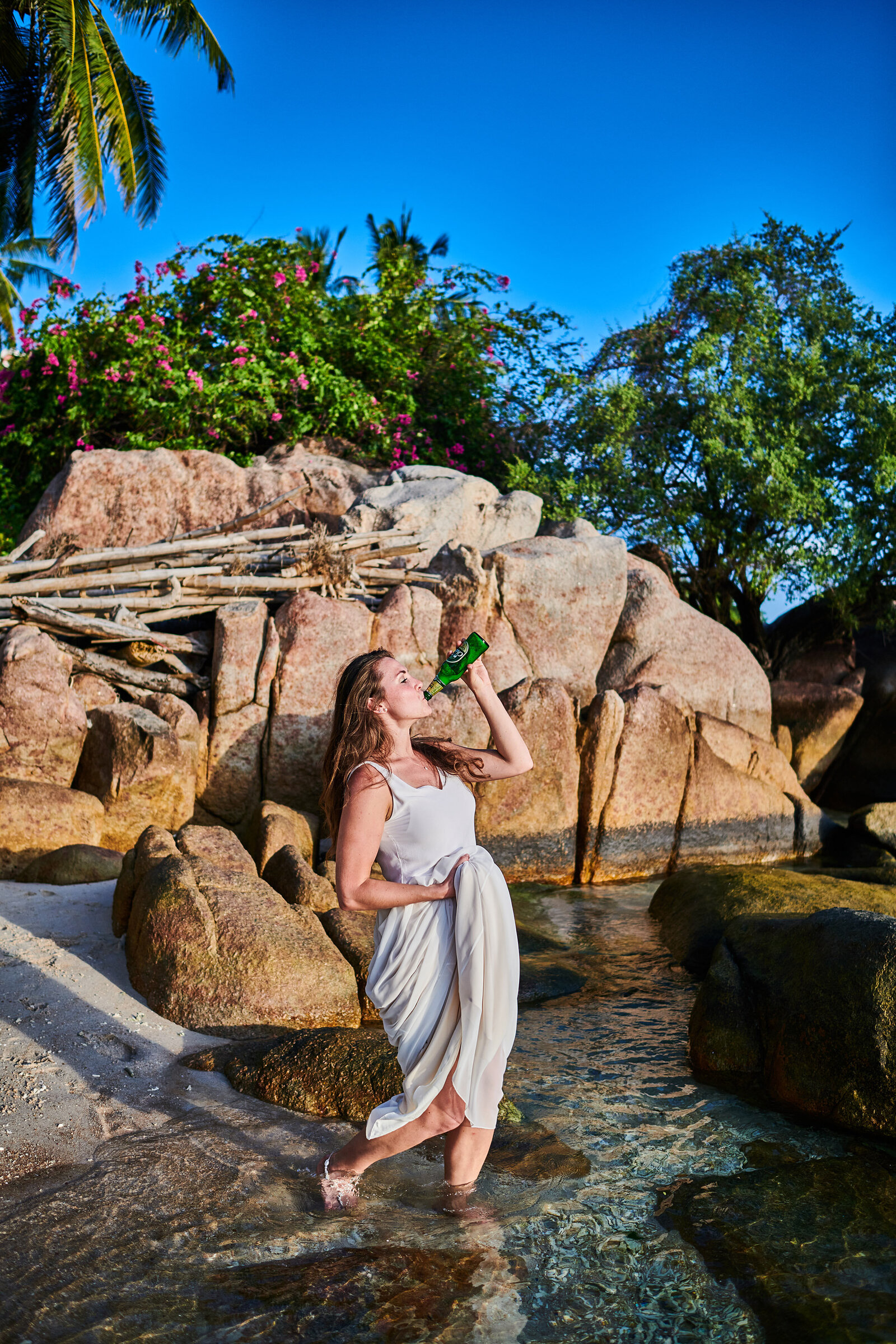 Bride drinking beer on beach