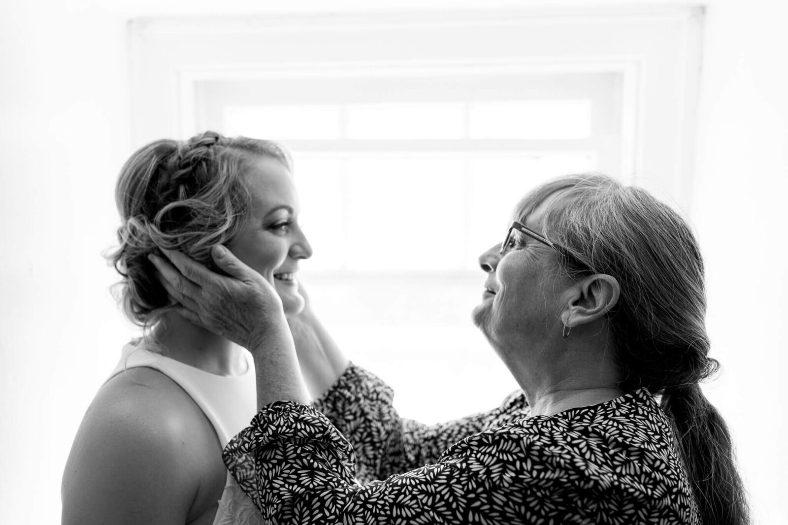 A mother embracing her daughter's face during the getting ready portion of a wedding day.