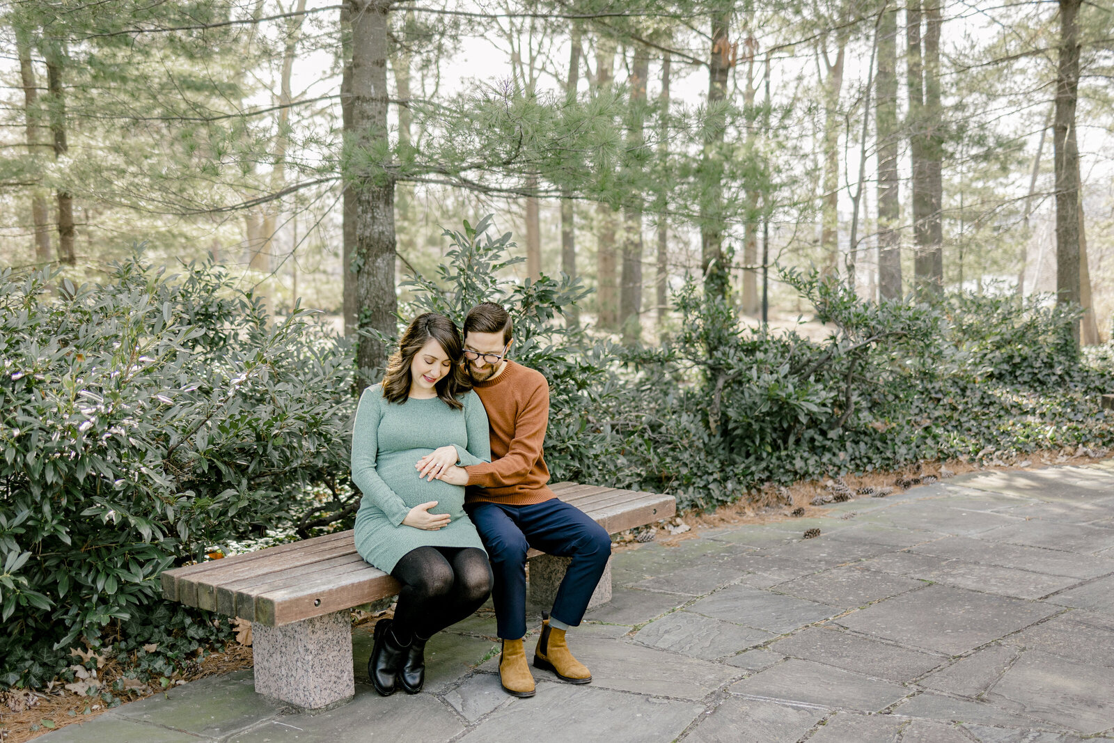 Couple sitting on bench looking at baby bump