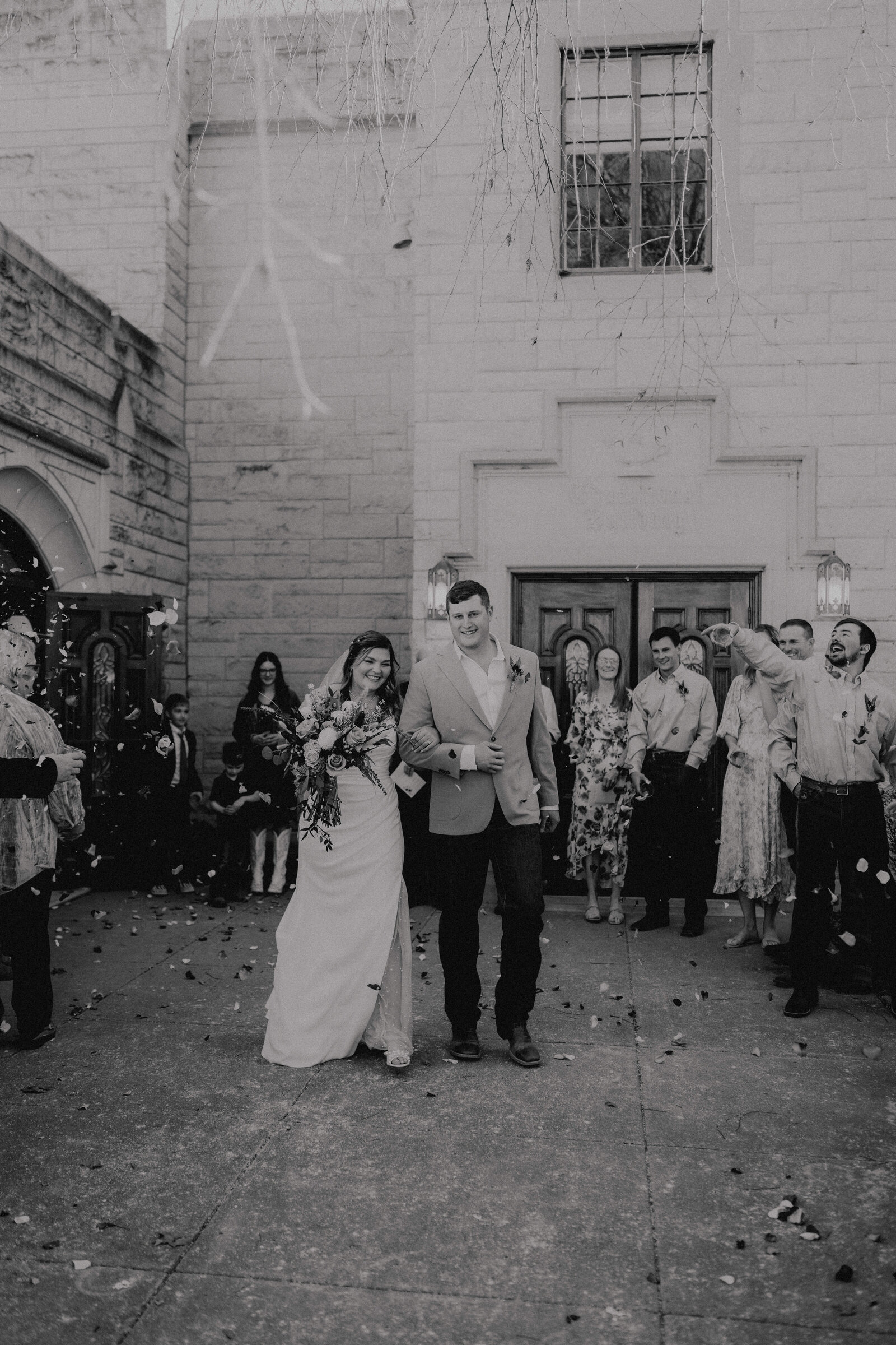 couple walking out of the church for the exit while guests throw flower petals