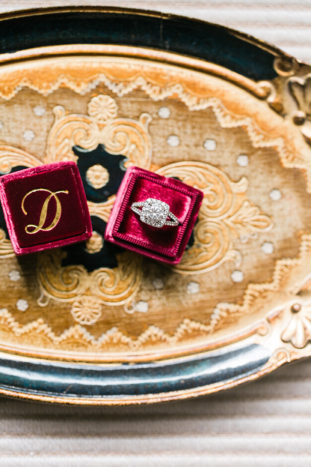 A stunning engagement ring staged with a jewel-toned decorative ring box by the Mrs. Box