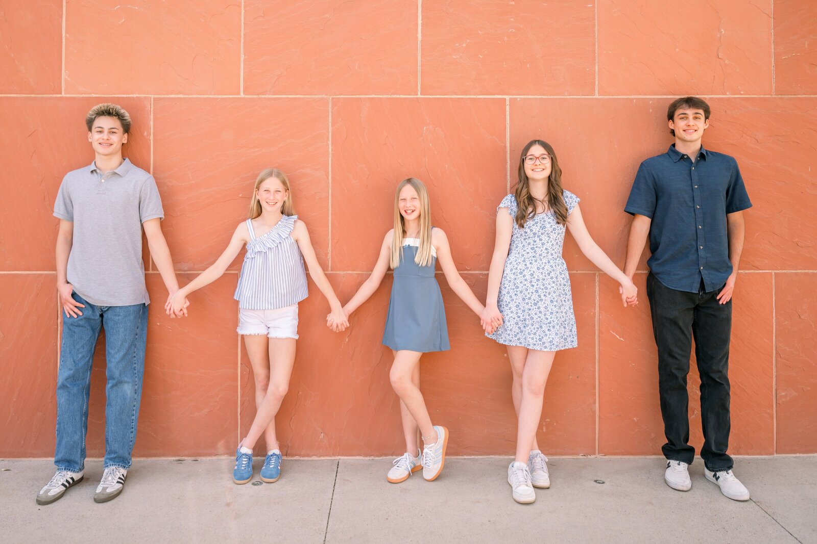 grandkids leaning against a red wall smiling at camera in oldtown scottsdale 