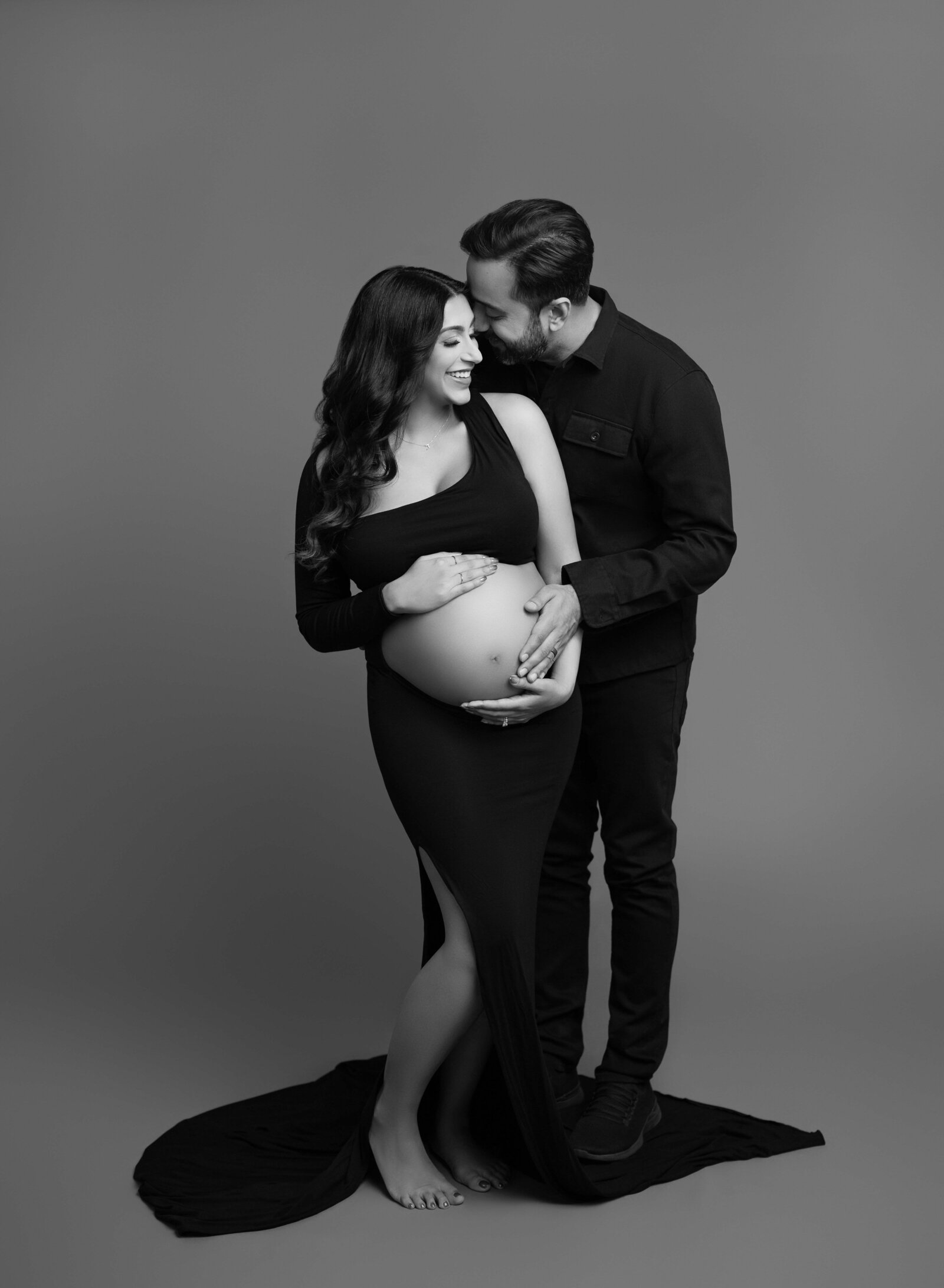 B&W photo of Mom and Dad holding belly and giggling. Jenni Nikki Photography took photo at Atlanta Maternity photo studio. 