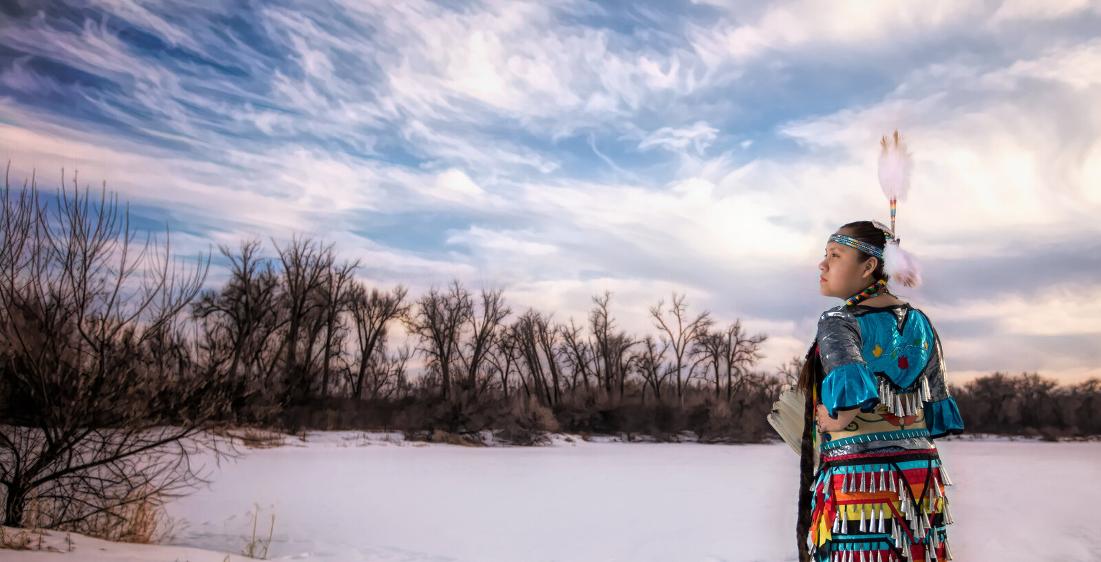 Senior Pictures in Native American Regalia. Blue jingle dress. Beautiful picture of client in the winter, wearing dress at River Front Park, Billings, MT, in winter.