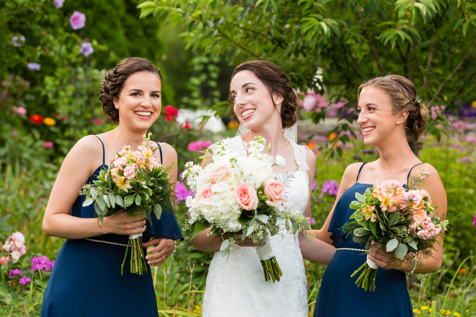 bride and bridesmaids holding flowers and laughing