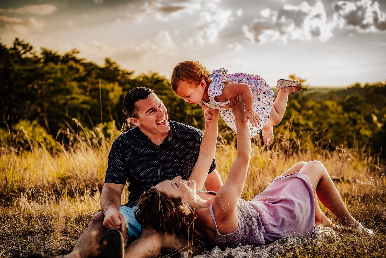 family holding a little girl in the air