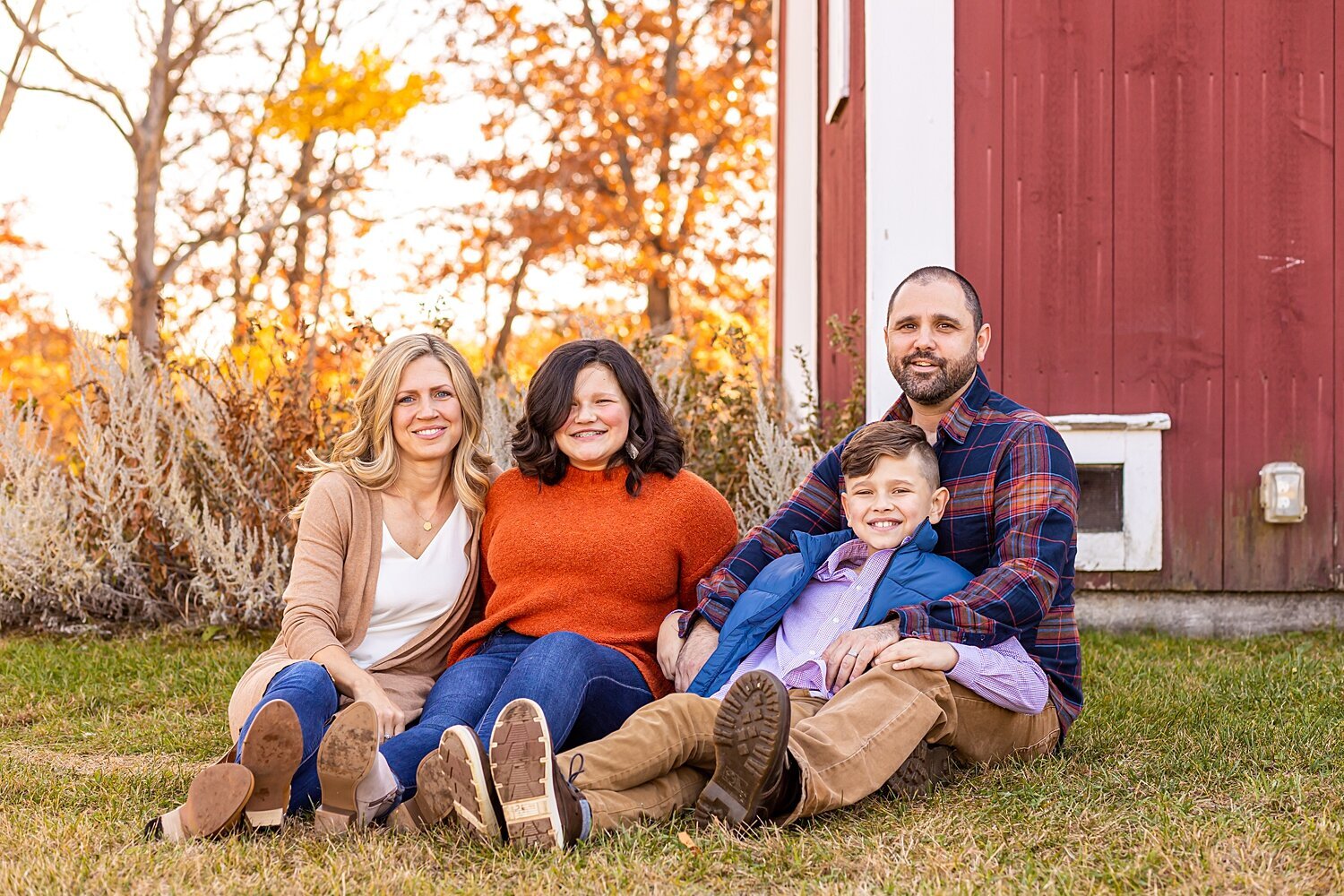 Family of four smiles at camera during fall family photo session in Londonderry, New Hampshire