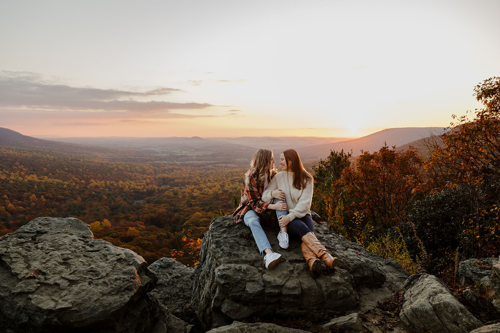 A couple sits on a rock at sunrise at Hawk Mountain in Pennsylvania