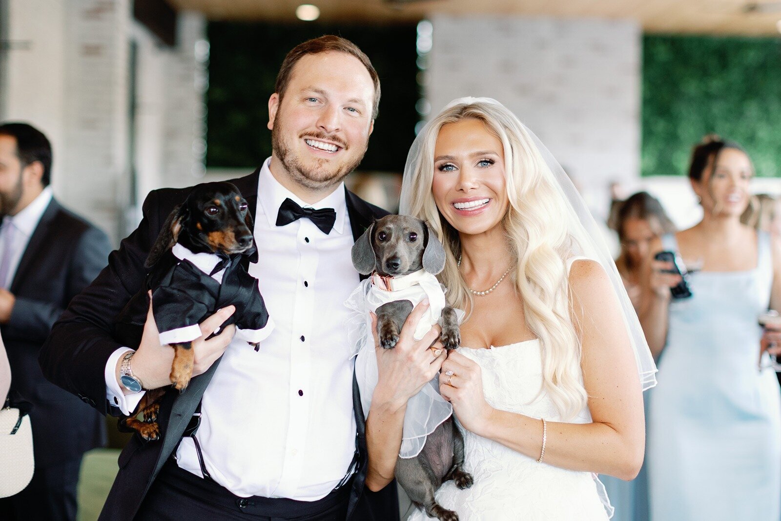 bride and groom holding two dogs posing happily on their wedding day at grbic events