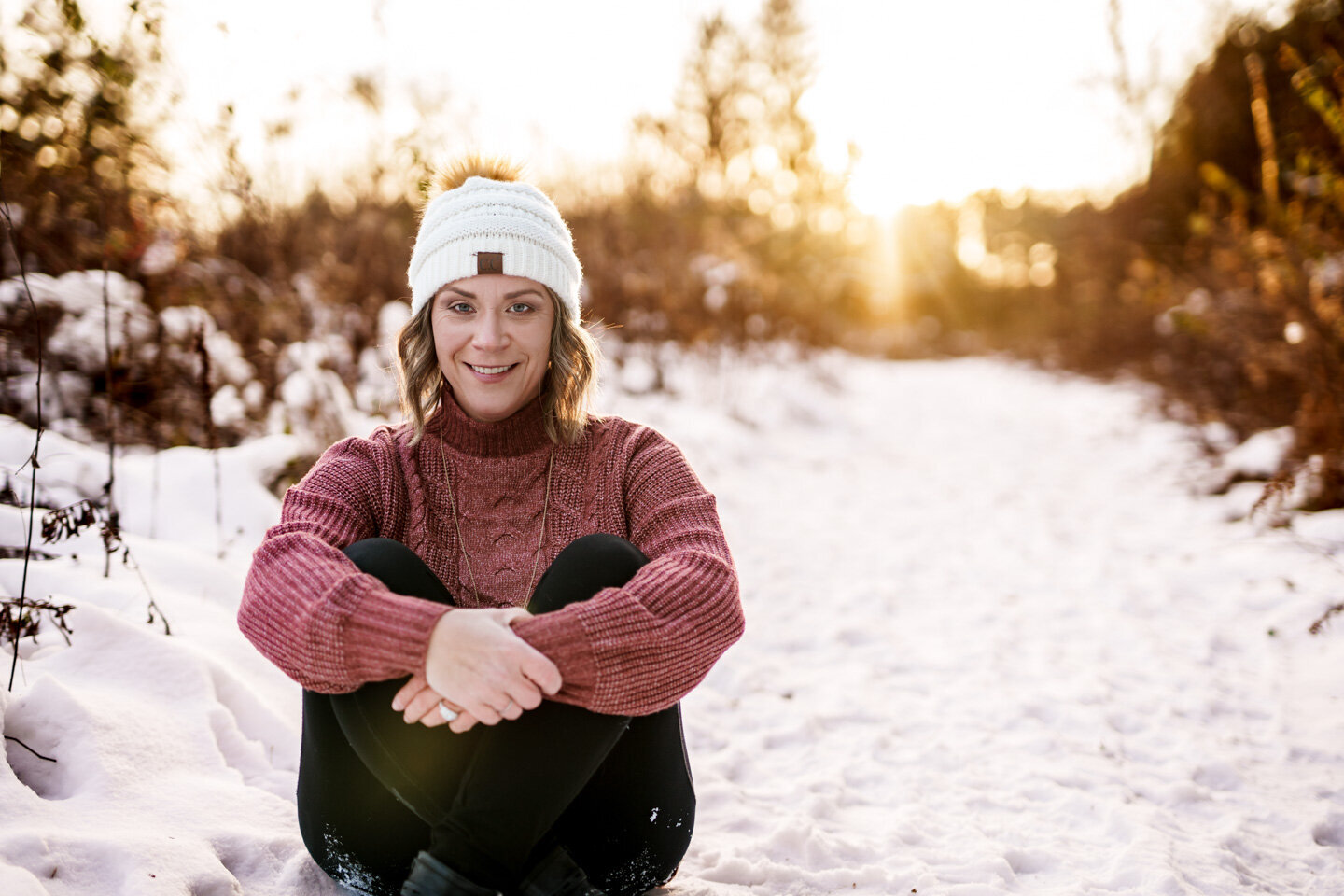 Jen Heller sitting in a snowy field at sunset