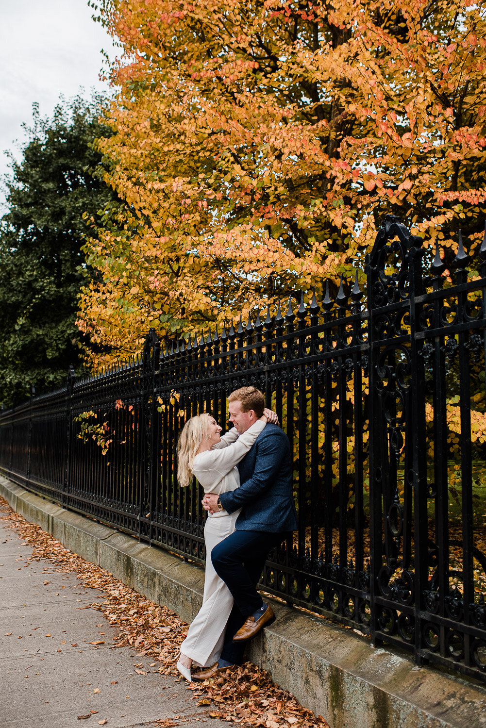 couple face each other by gate and  tree in fall