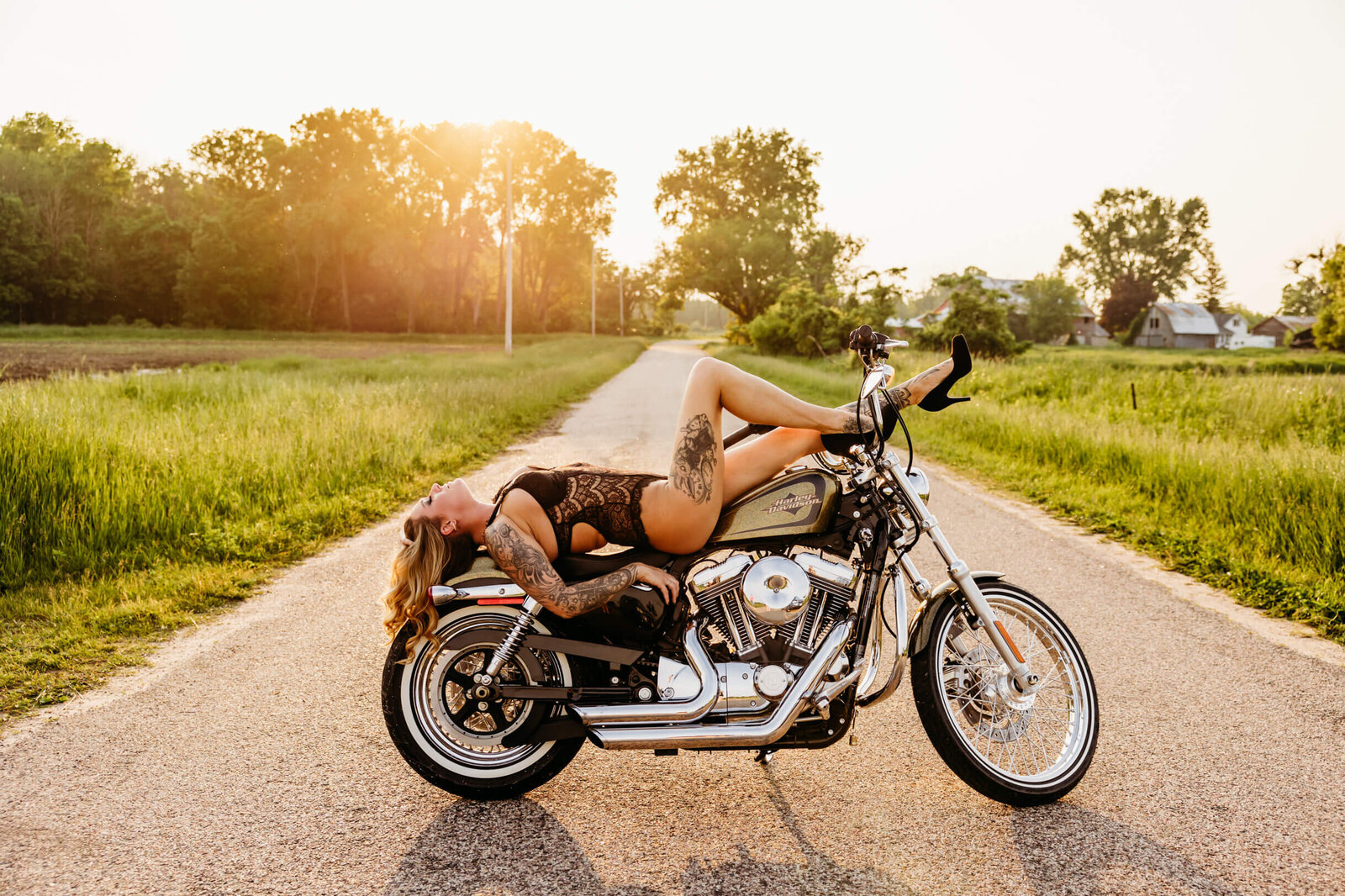 stunning portrait of a woman in a lace bodysuit laying on a harley davidson motorcylce for her wisconsin boudoir photography session.