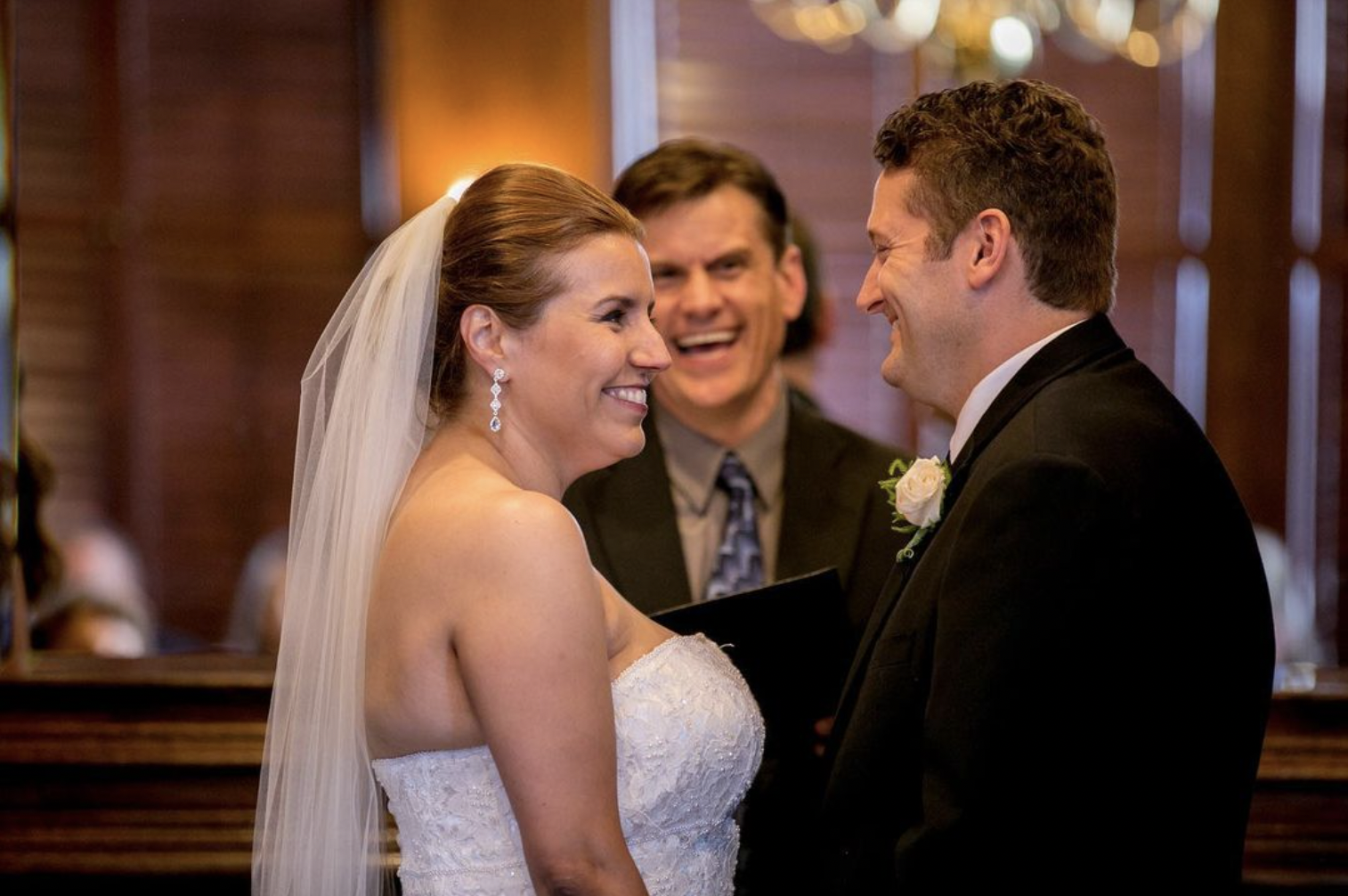Bride, groom, and wedding officiant laugh during wedding ceremony
