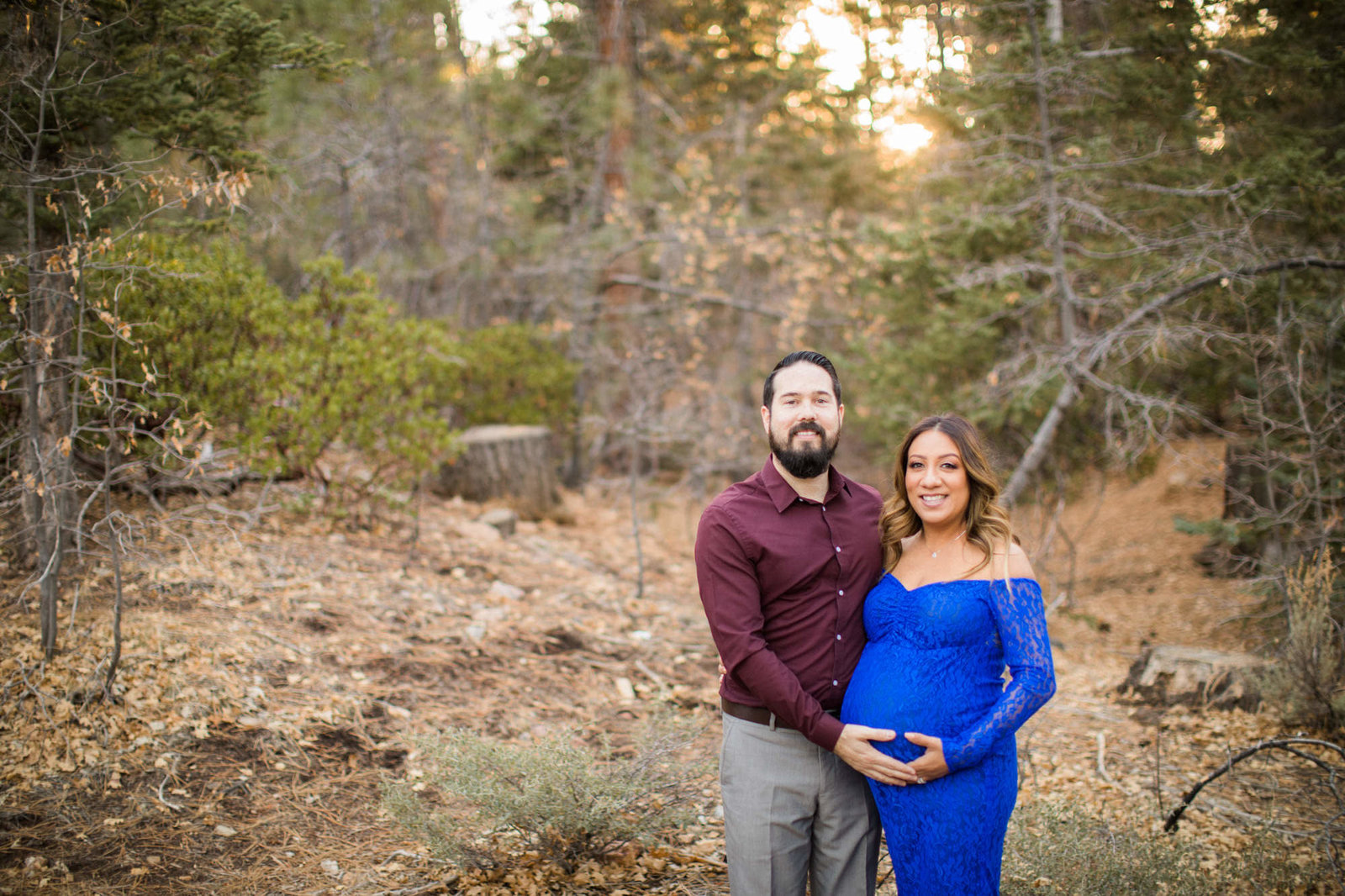 Parents pose for maternity photos in the mountains as they place their hands on the wife's belly