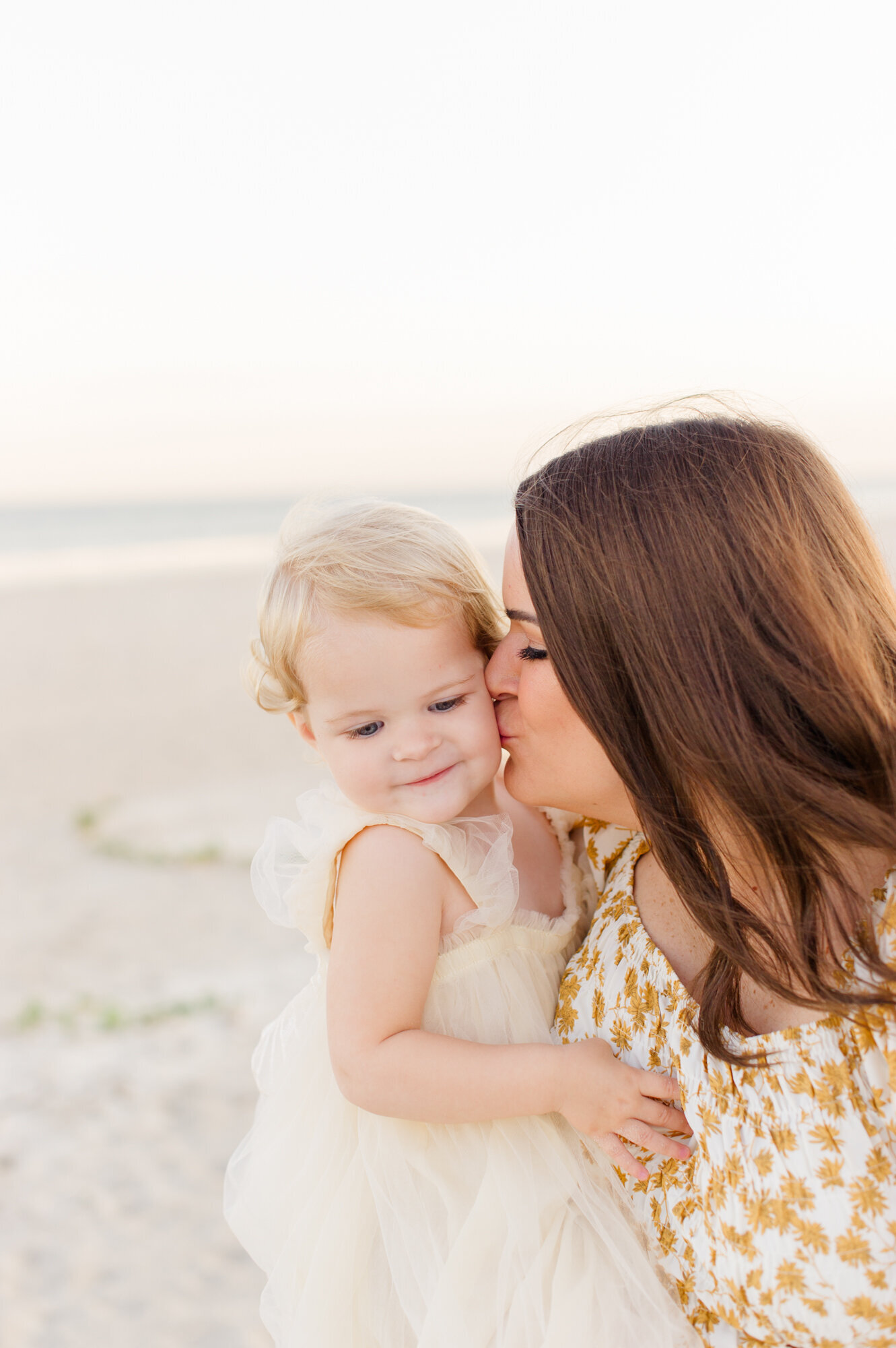 Melbourne Fl mom kisses daughter on the cheek at the beach during their family photos