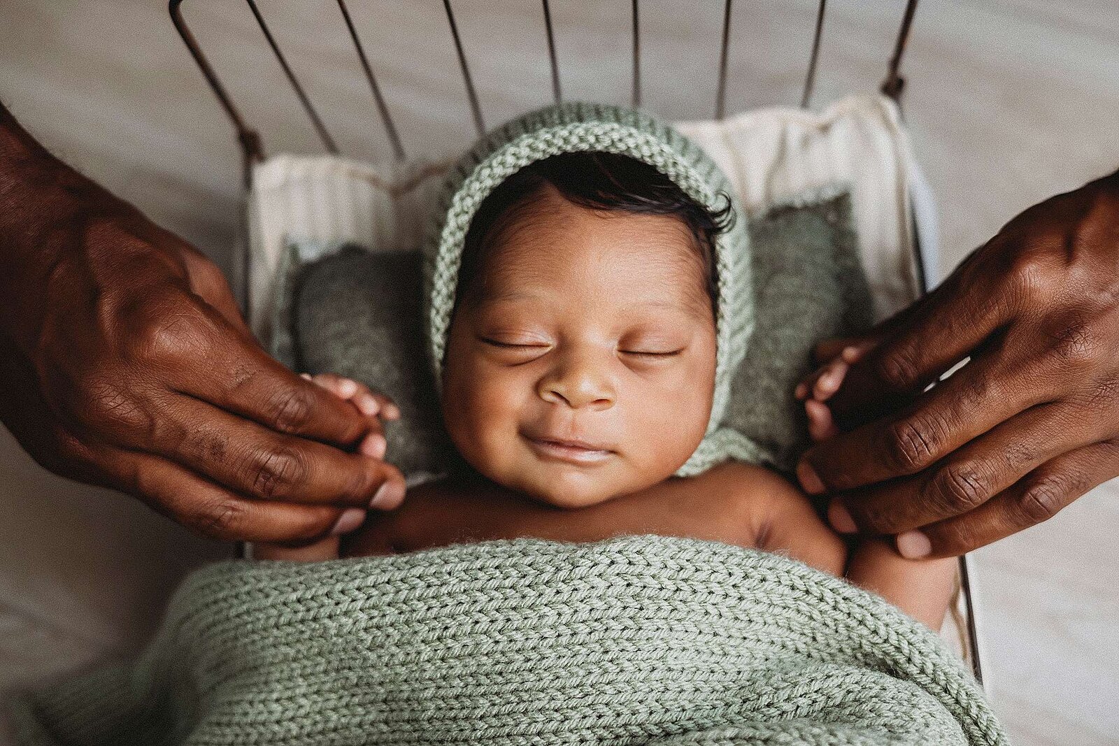A serene baby swaddled in a green blanket, beautifully photographed by Bia Schaefer during an in-home newborn session in Orlando.