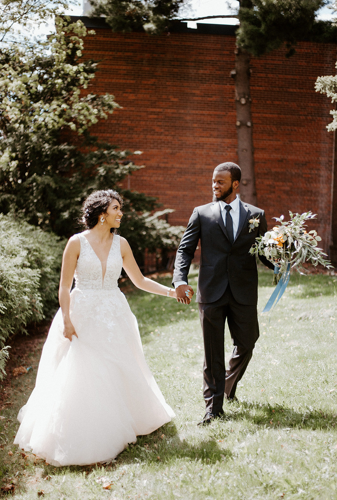 Couple holding hands with the groom holding his brides bouquet on their Minneapolis Wedding Day