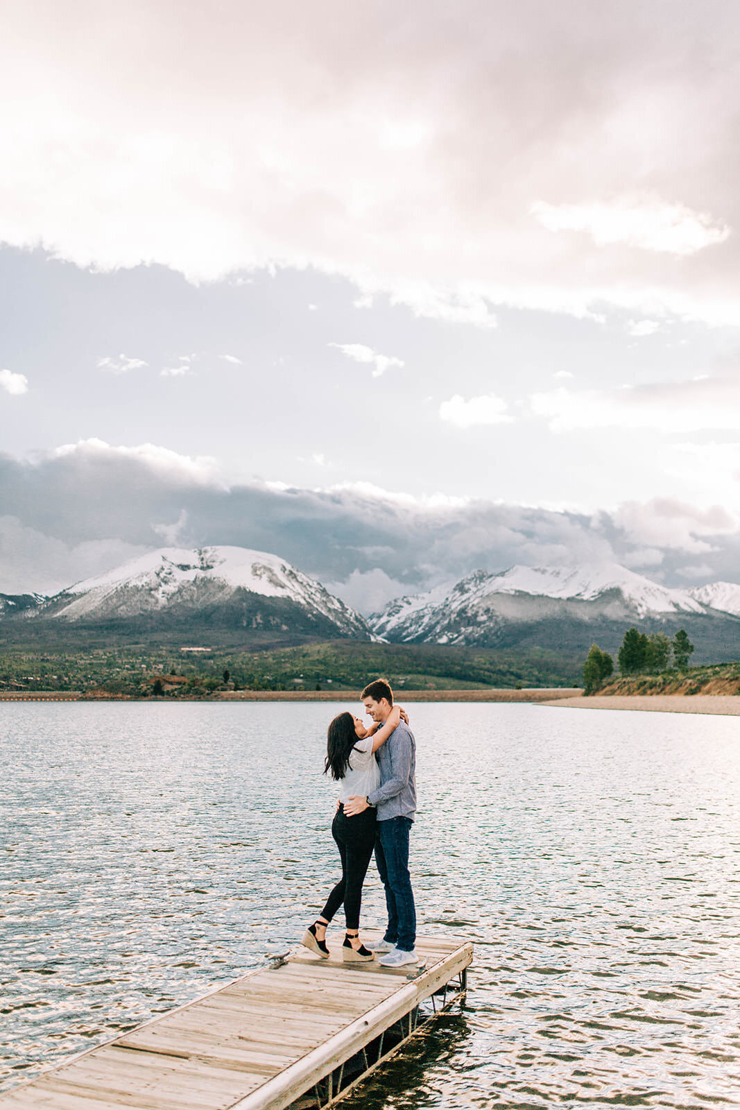 Couple hugging on dock at Lake Dillon during summer engagement photos in Colorado