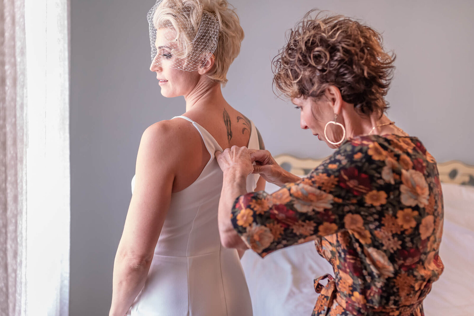 Mother of the bride buttoning her bride's gown