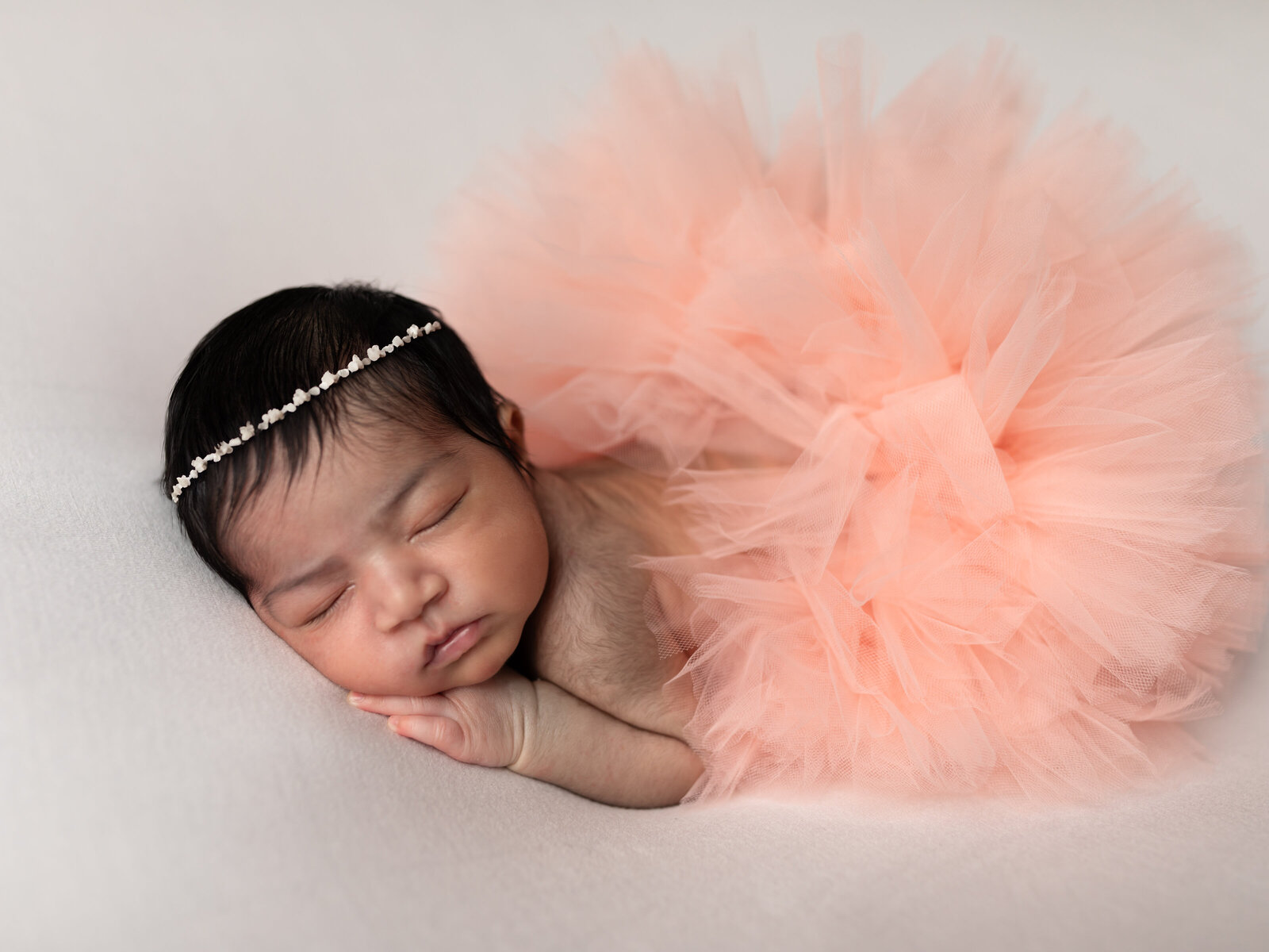 newborn baby girl in pink tutu posed for studio newborn phototography