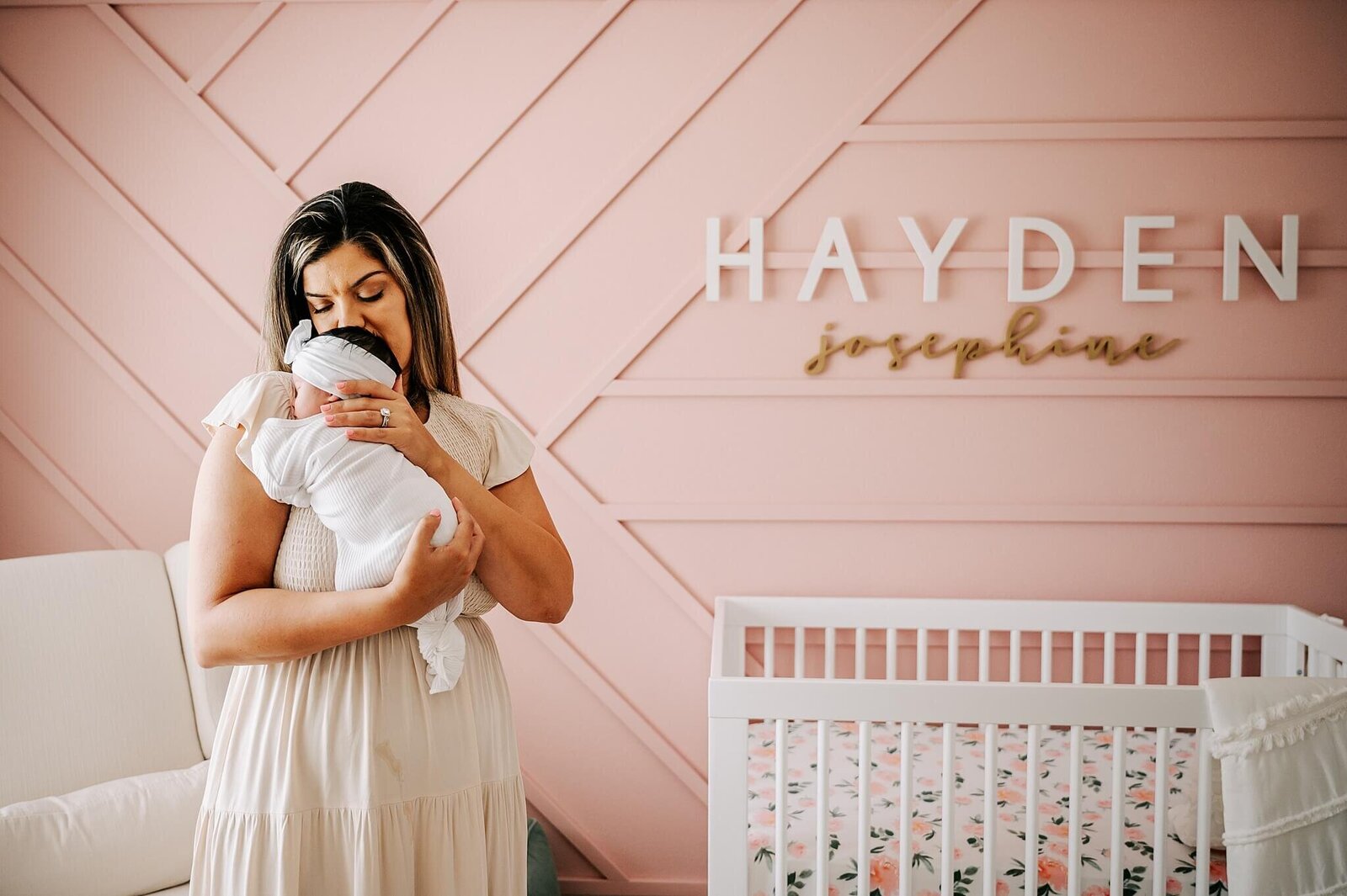 New mom snuggling her baby dressed in white during a lifestyle newborn session in Orlando, FL