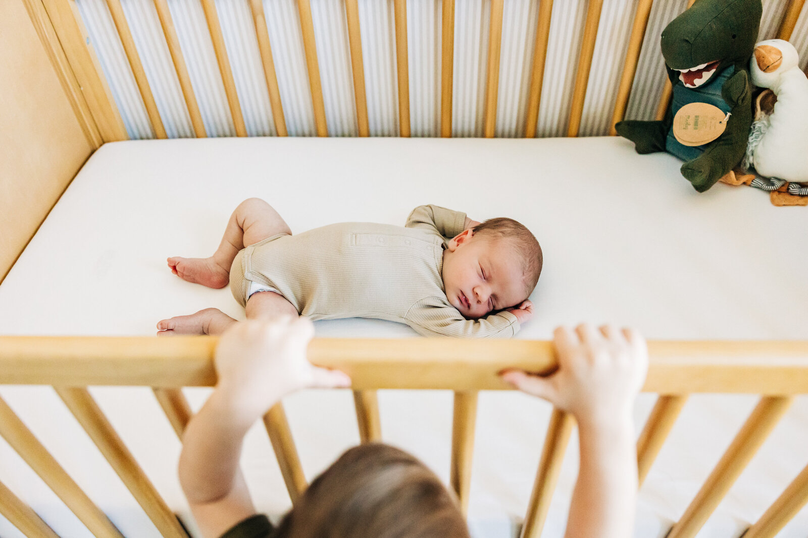 An older sibling gently interacting with the newborn, showcasing the excitement and love of welcoming a new family member.