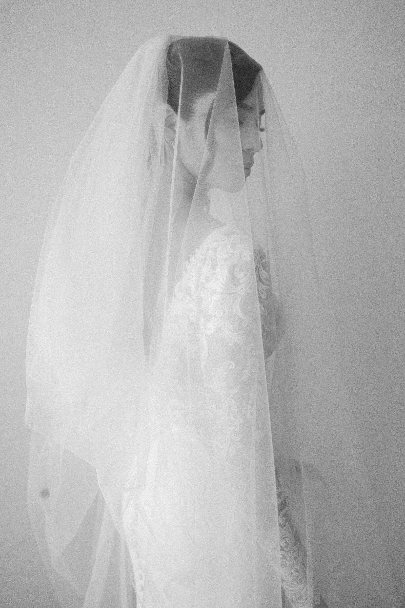 Bride posing elegantly with her sophisticated vail draped over herself. Photo by Maggie Alvarez Photography