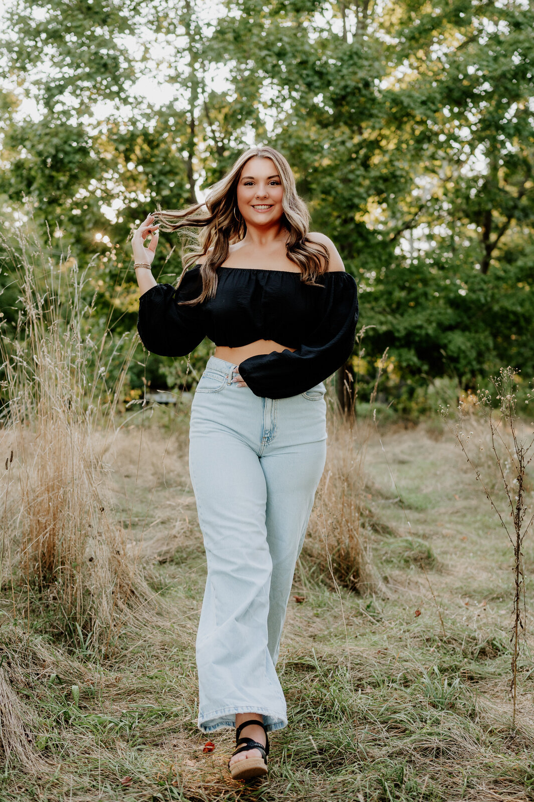 Girl walking towards the camera wearing jeans and a black tube top.