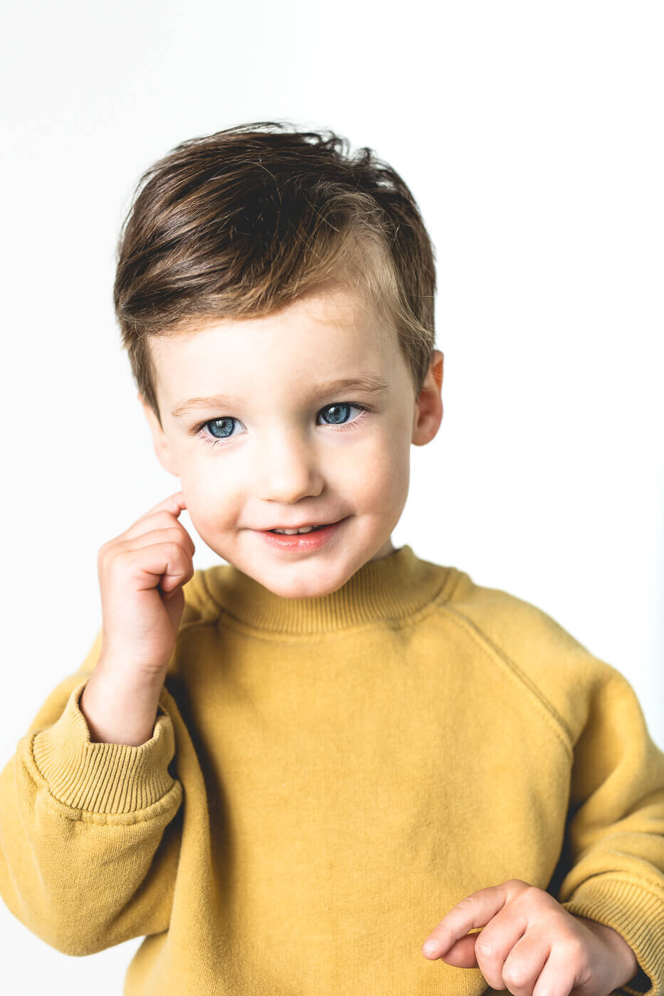 Child in yellow sweater smiling shyly
