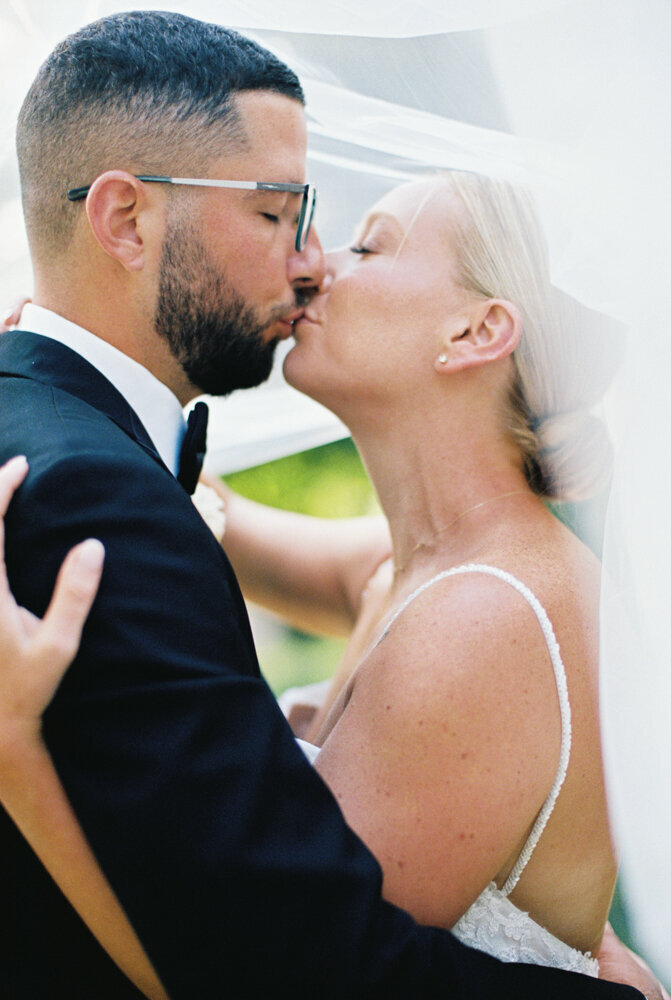 bride and groom kissing under veil