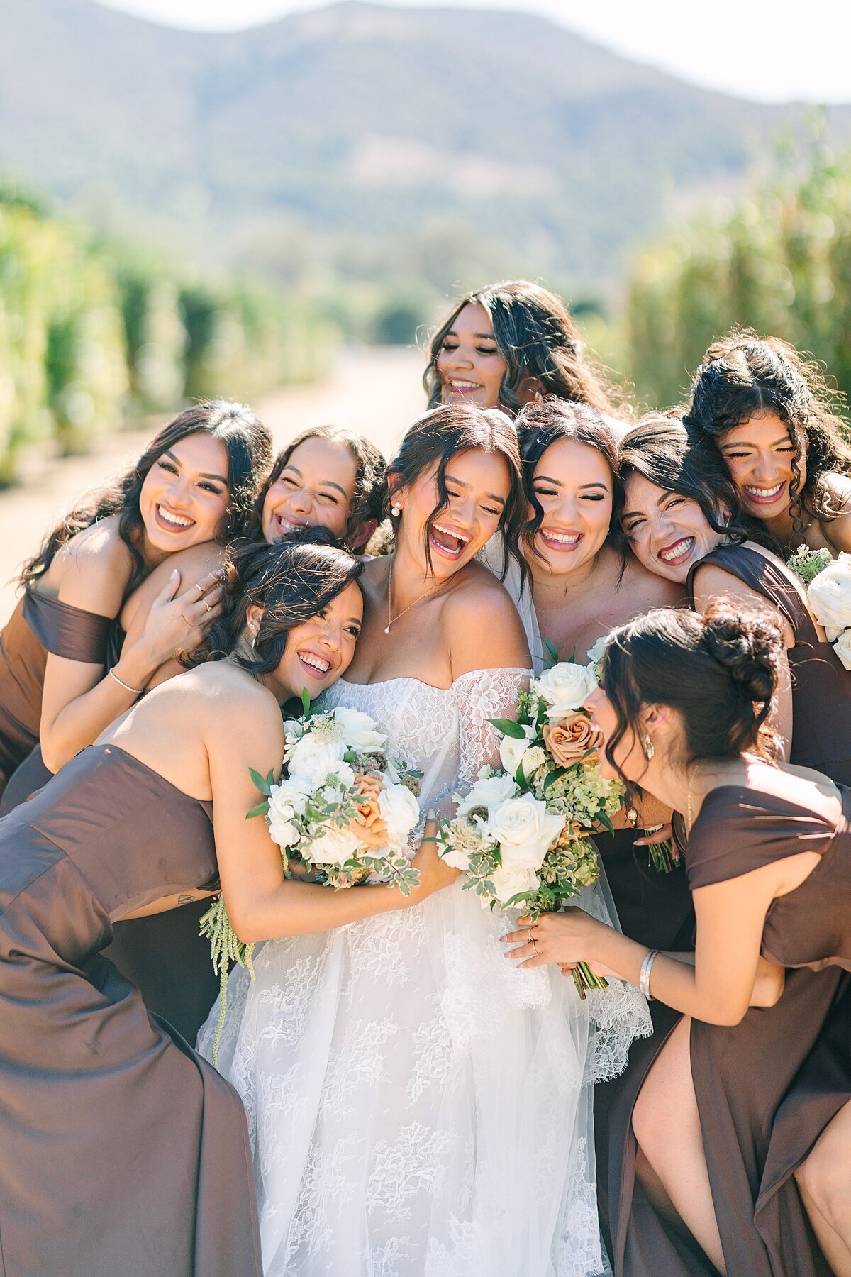 Bridesmaids hugging bride on her wedding day before the ceremony with their bouquets at Rancho Guejito.