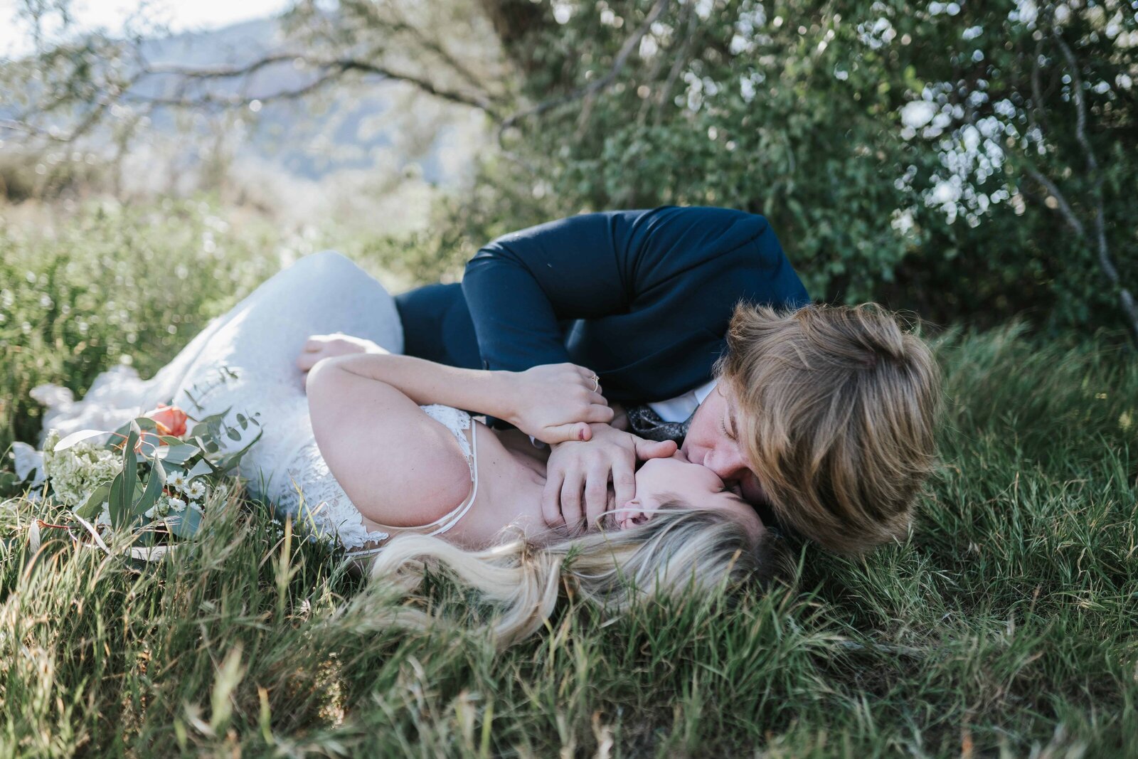 Lake Tahoe wedding photographer captures bride and groom rolling around in grass after Lake Tahoe wedding