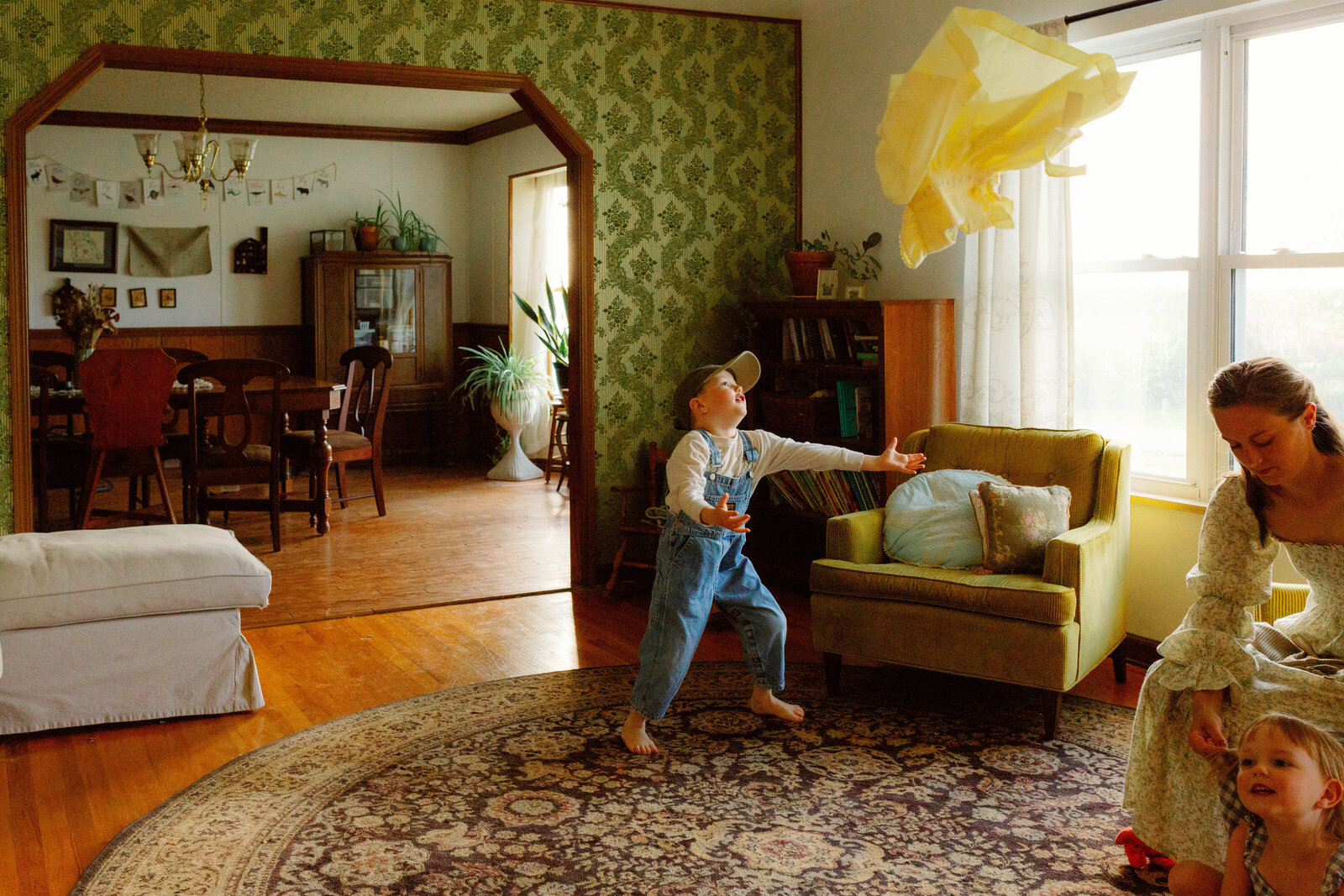 Baby lying on a colorful blanket with legs visible and mother’s arms resting beside him, capturing intimate, tender, and authentic family moment